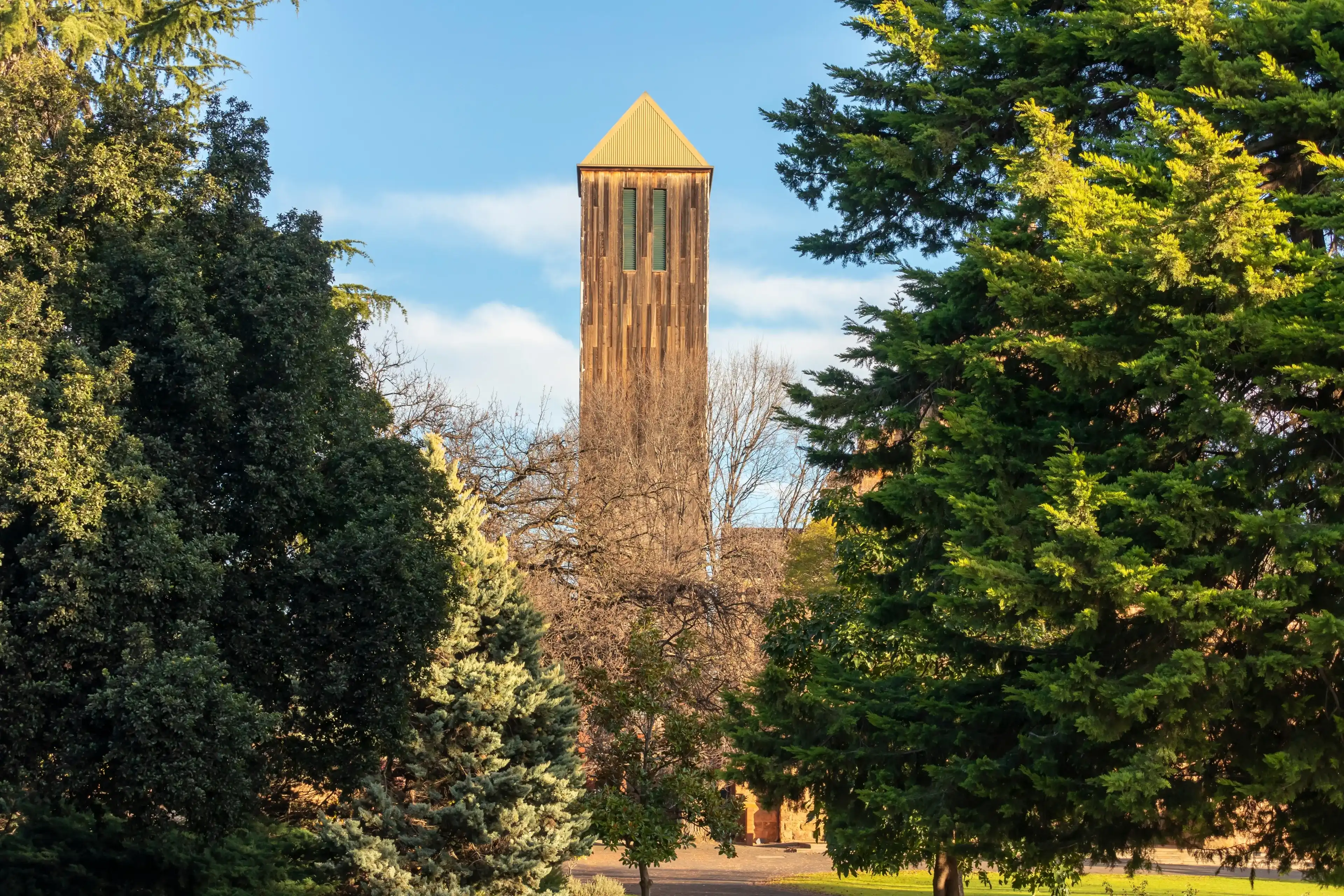 Photograph of the tall church tower against a blue sky in Wangaratta surrounded by large green trees in regional Victoria in Australia Photograph of the tall church tower against a blue sky in Wangaratta surrounded by large green trees in regional Victoria in Australia