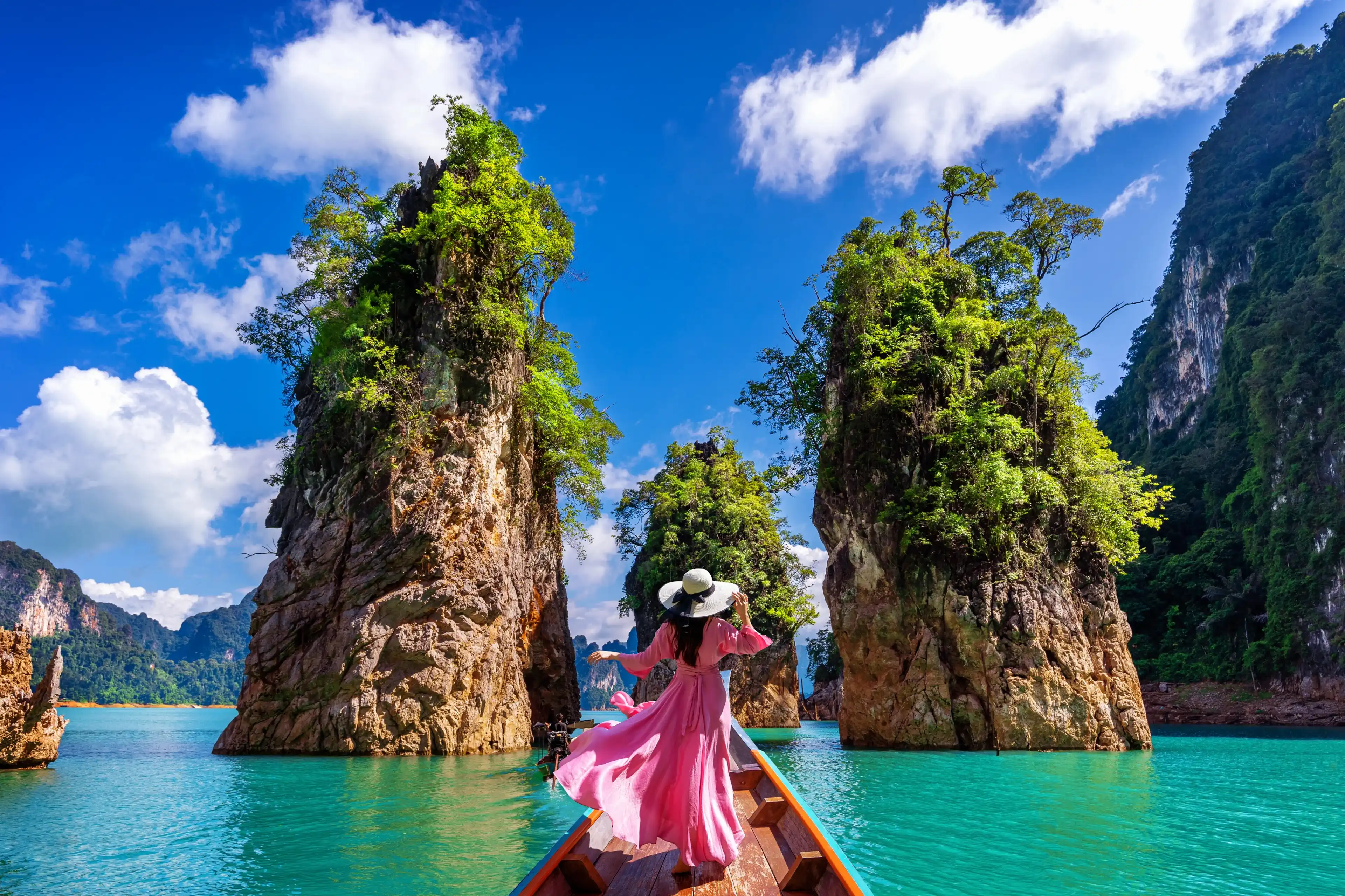 Beautiful girl standing on the boat and looking to mountains in Ratchaprapha Dam at Khao Sok National Park, Surat Thani Province, Thailand. Beautiful girl standing on the boat and looking to mountains in Ratchaprapha Dam at Khao Sok National Park, Surat Thani Province, Thailand.