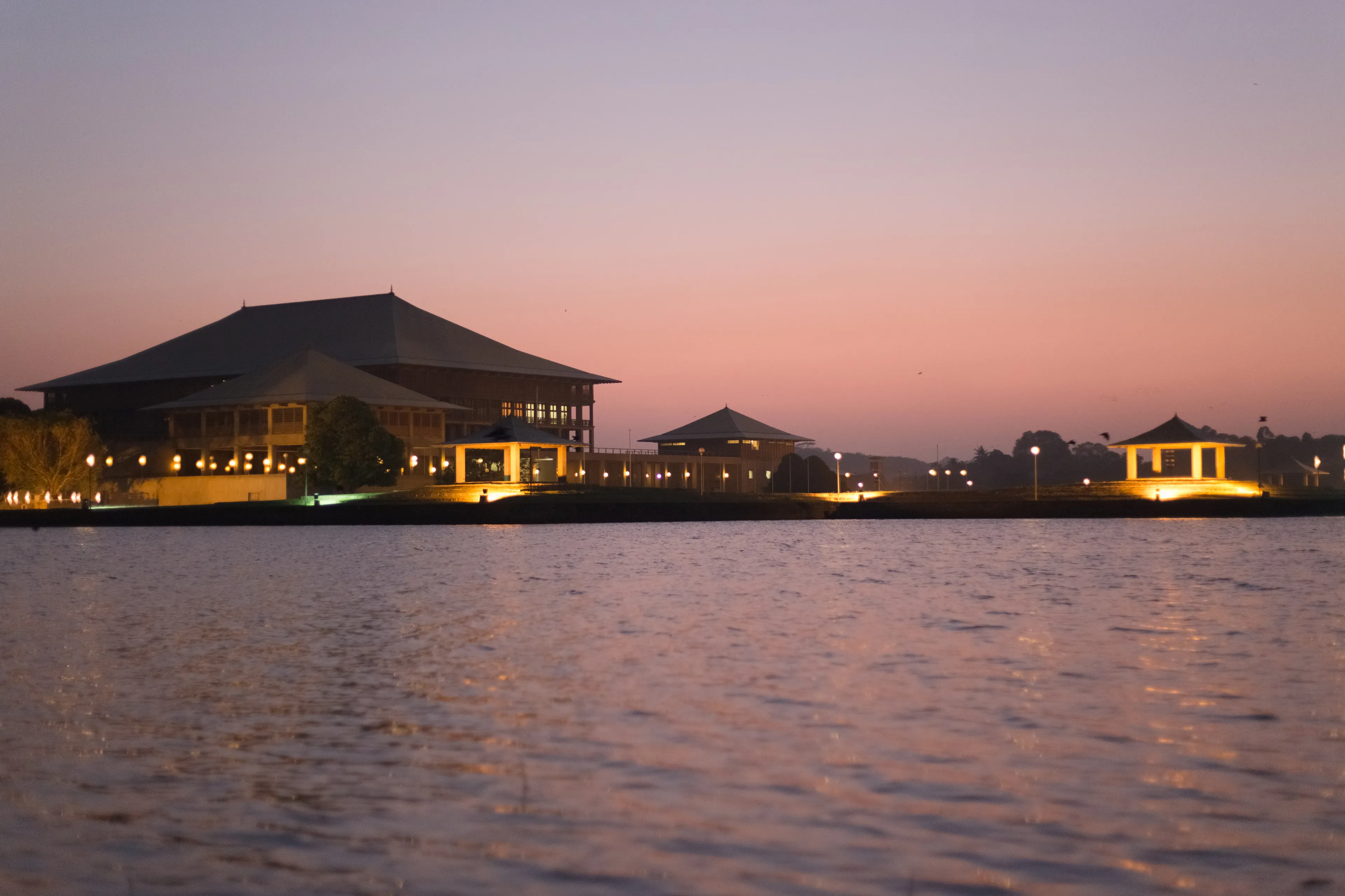 Parliament of Sri Lanka Ceylon, across Diyawanna lake waterscape in clear sunset background in evening night lights on at Colombo.