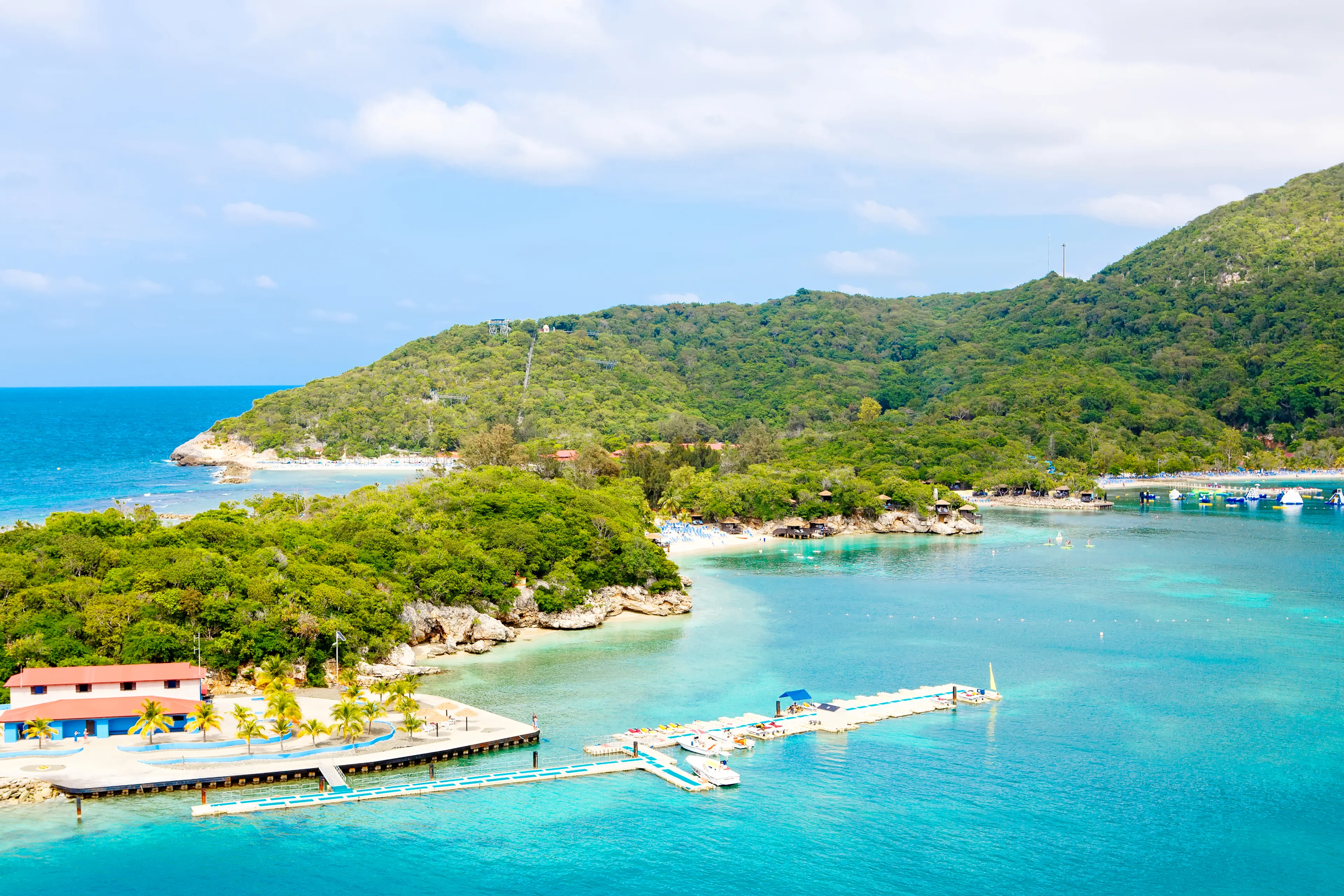 Beach and tropical resort, Labadee island, Haiti. Exotic wild beach with palm and coconut trees against blue sky and azure water