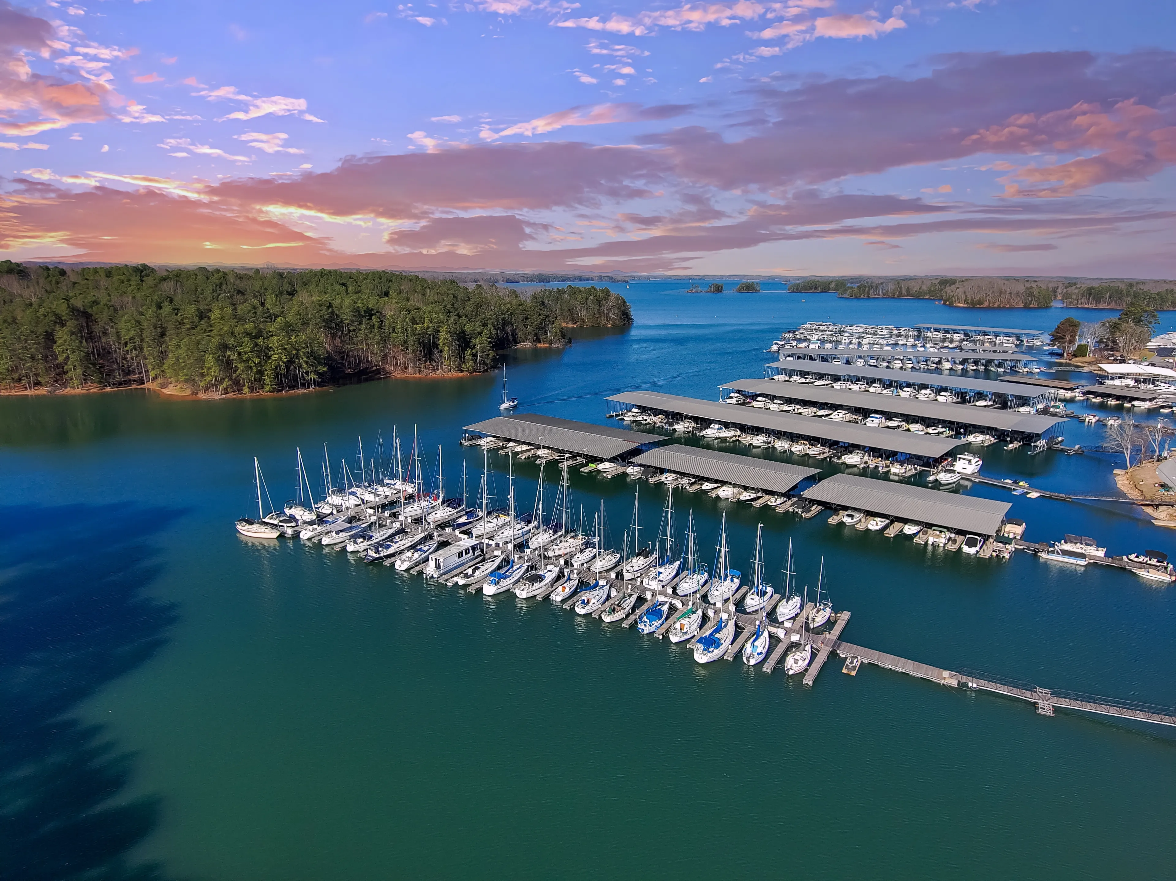 Boats and yachts docked and sailing in the marina on Lake Lanier with lush green trees and and powerful clouds at sunset in Cummings Georgia USA