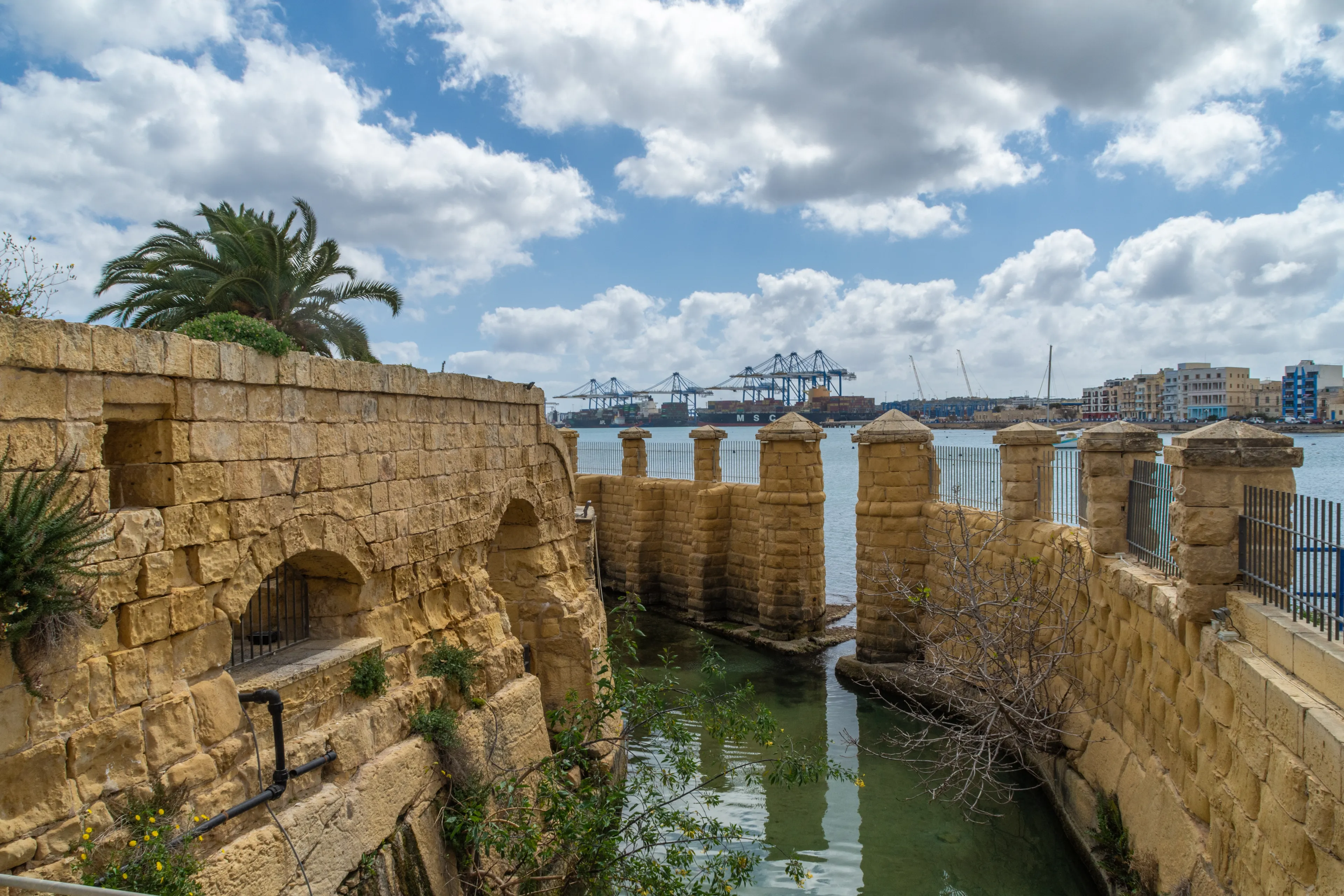 Birżebbuġa, Malta - March 14th 2021: The moat around the Ferretti Battery built by the Order of Saint John in 1716. The Malta Freeport can be seen in the background.