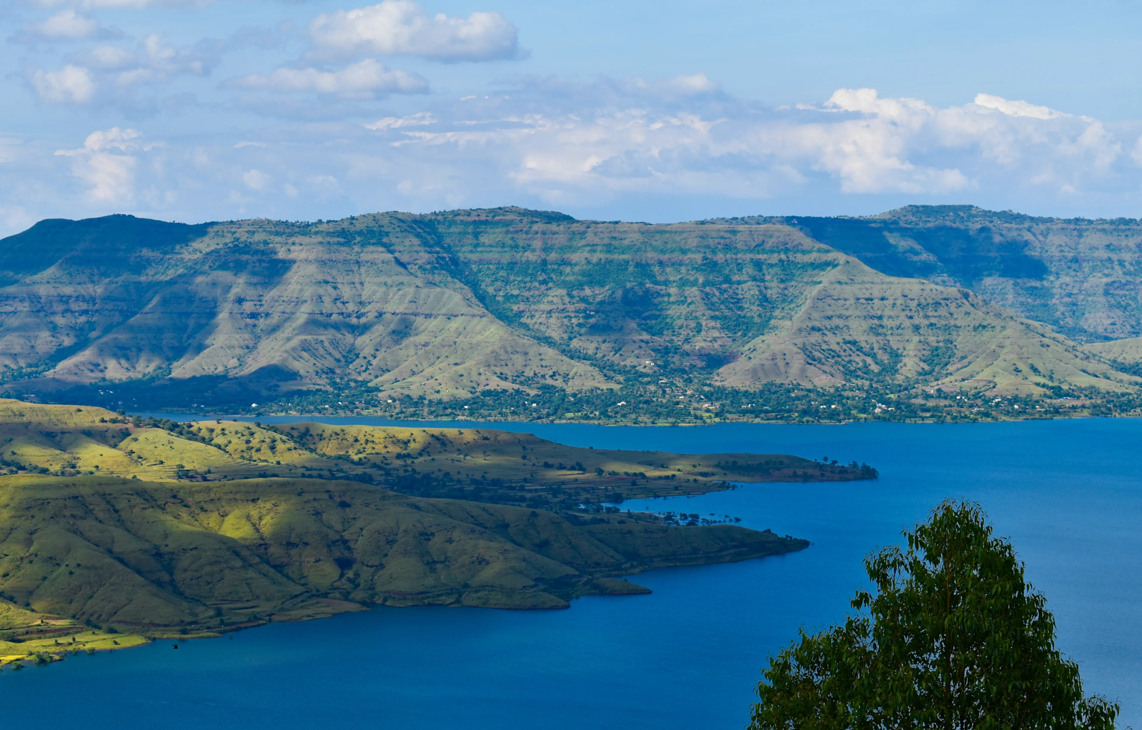 A Beautiful tourist destination, a valley with blue water river / lake, green hill / mountain on backdrop and blue sky. situated in Panchghani, mahabaleshwar, Maharashtra