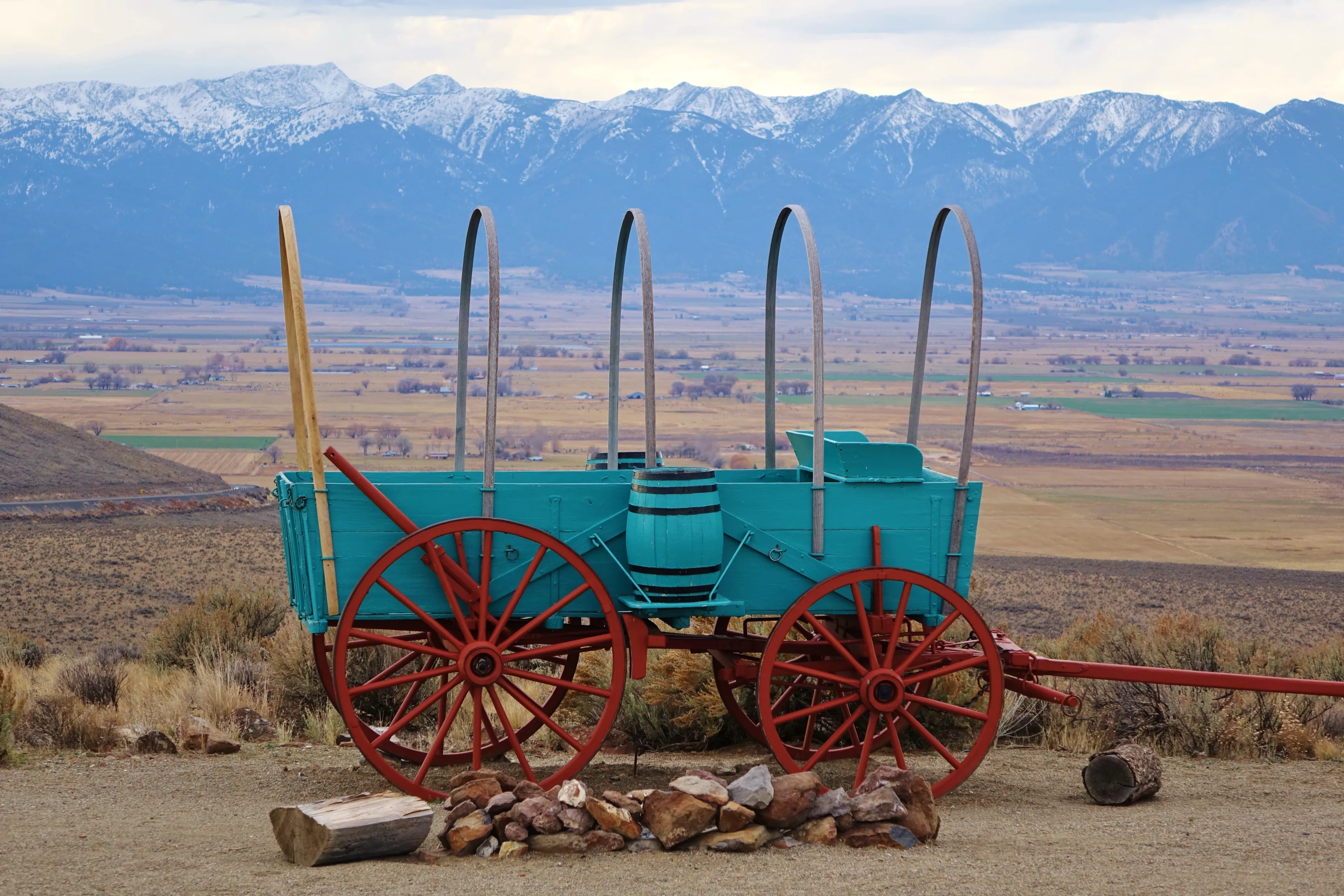 Oregon Trail Interpretive Center near Baker City, OR features several old wagons and beautiful views. This uncovered wagon sits above a sagebrush filled valley with the Blue Mountains in the distance.