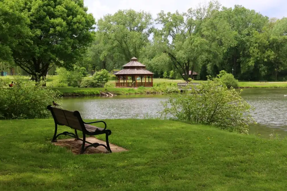 Midwest nature background with city park view.Beautiful late spring landscape with bench in a foreground, trees around the pond and wooden gazebo in a city park.Lakeview park, Middleton, Madison area. Midwest nature background with city park view.Beautiful late spring landscape with bench in a foreground, trees around the pond and wooden gazebo in a city park.Lakeview park, Middleton, Madison area.
