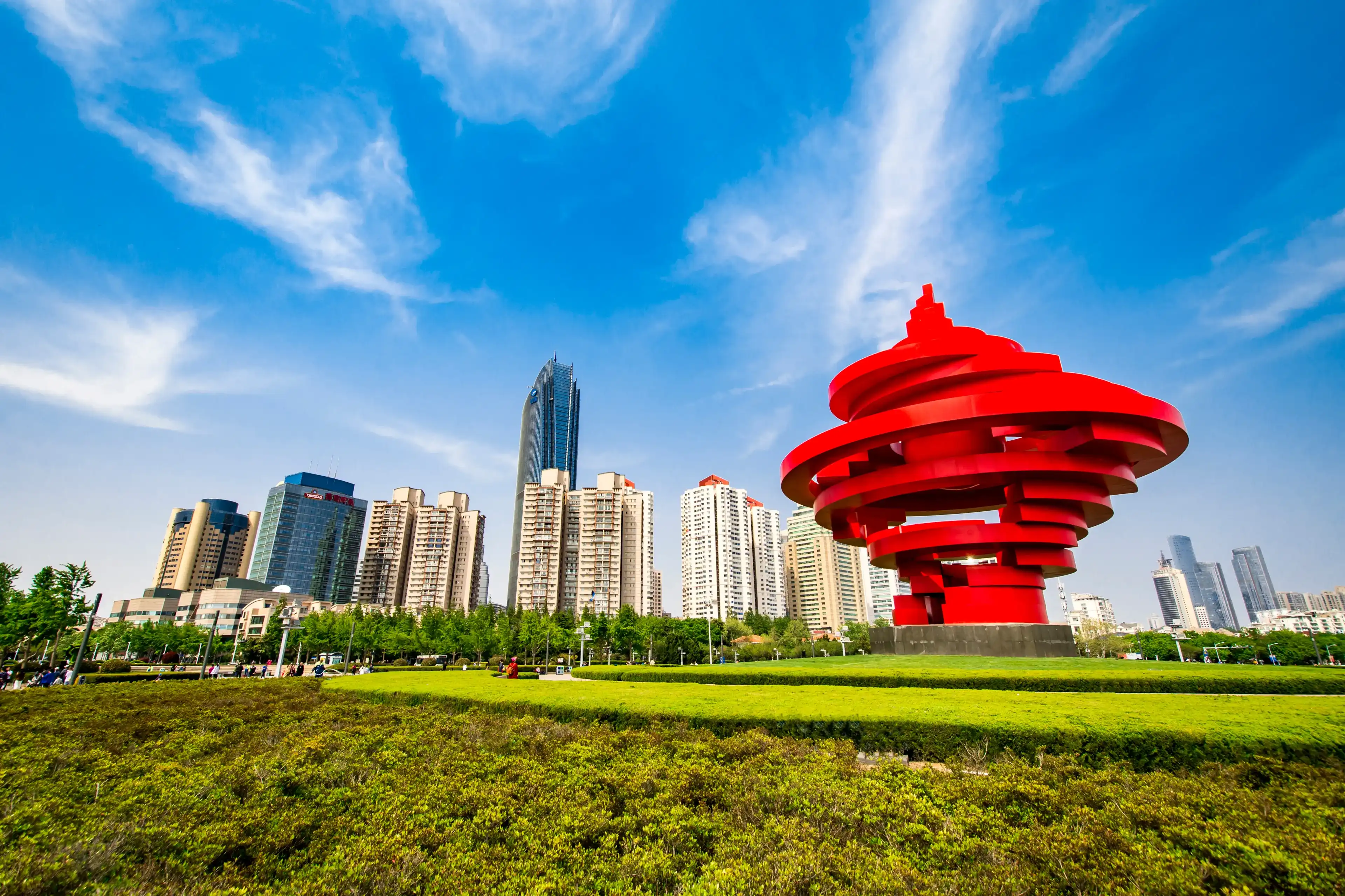 QINGDAO, SHANDONG, CHINA - MAY 11, 2019: "May Fourth" Wind sculpture in May Fourth Square with Qingdao downtown skyscrapers in the background