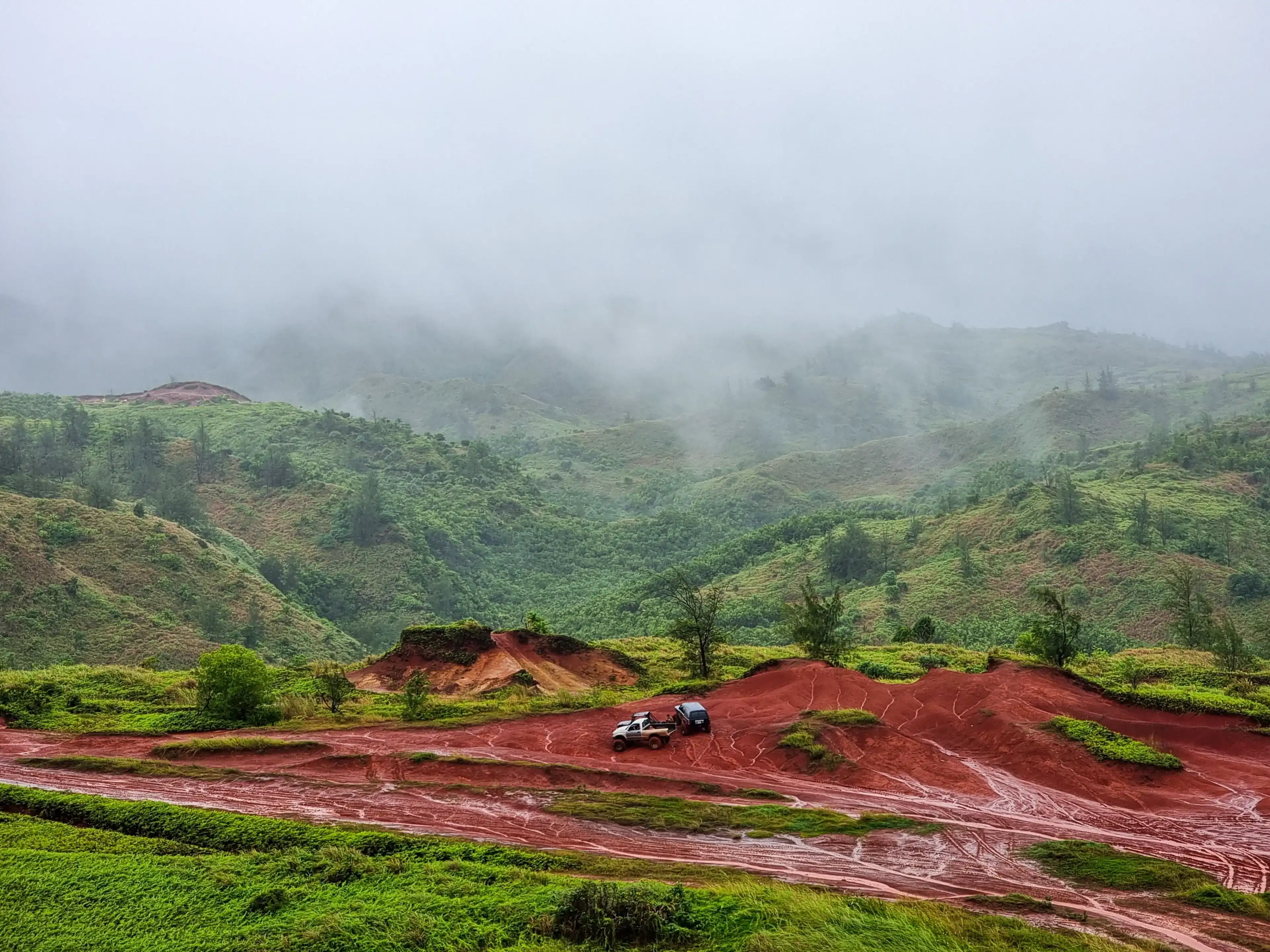 The three off-road cars in the valley surrounded by green mountains. Yona, Guam. The three off-road cars in the valley surrounded by green mountains. Yona, Guam.