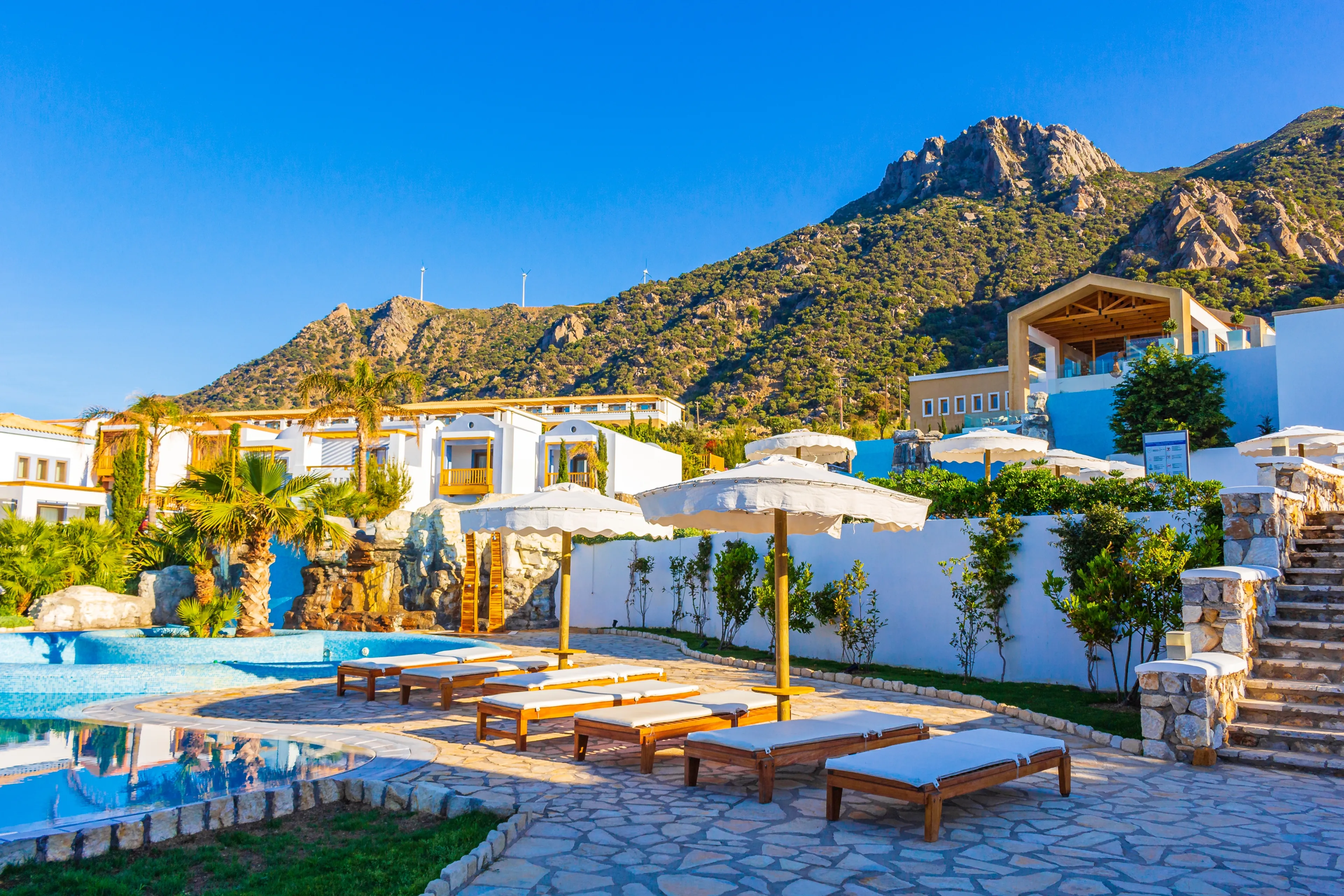 Kardamaina Kos Greece 04. May 2015 Luxury resorts and beaches with sun loungers and umbrellas under the Oros Dikaios Dikeos mountain natural coastal landscapes Kos Island Greece with blue sky.