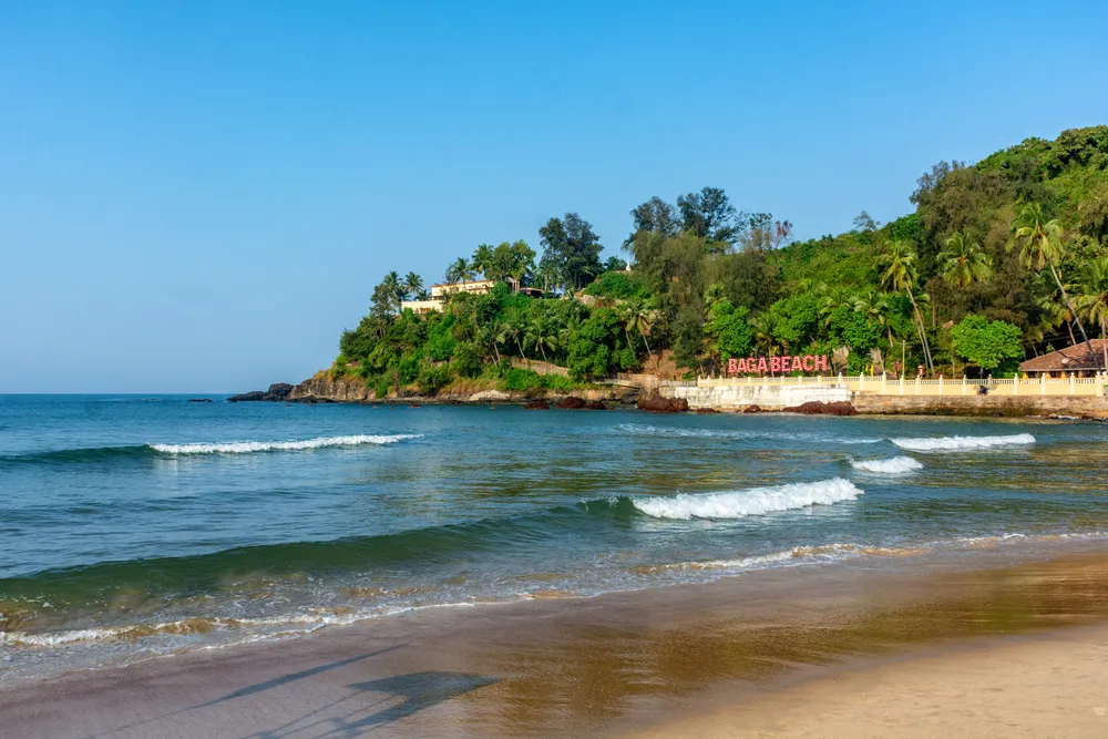 Beautiful Baga beach with waves lapping up onto the shore in a perfect sunny day