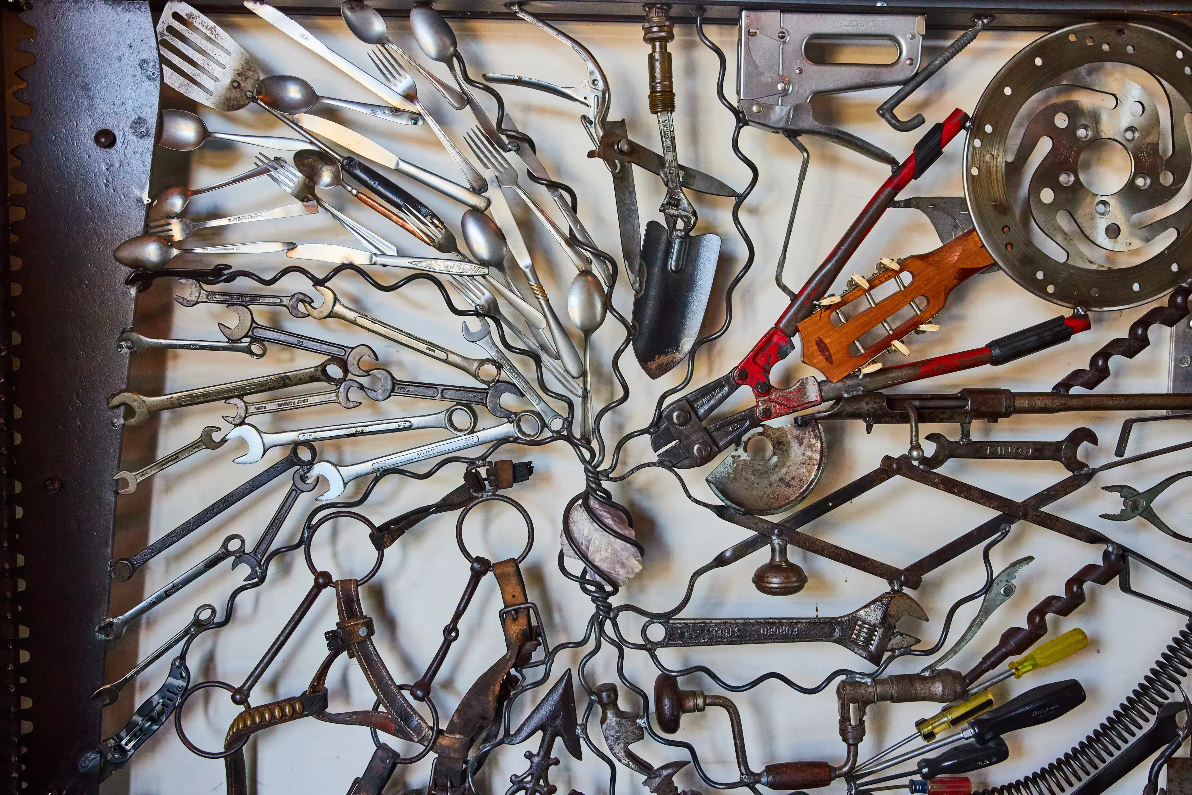 Wall of interconnecting tools and assorted metal objects connected by wires with white background Wall of interconnecting tools and assorted metal objects connected by wires with white background
