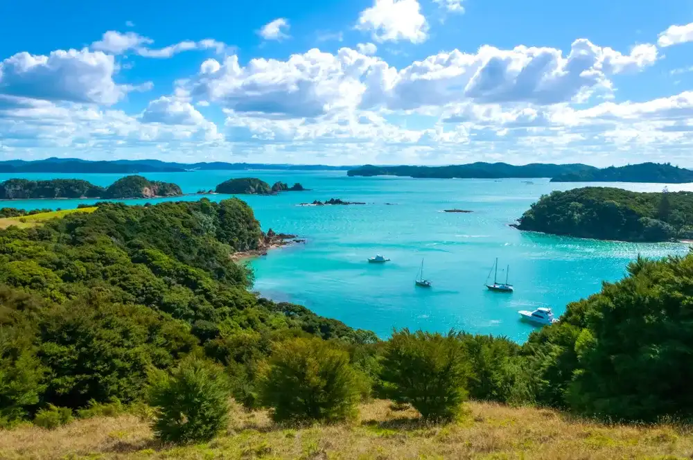 Aerial view of the small ships, boats and yachts in clear and calm turquoise color waters of the Bay of Islands near Urupukapuka Island, Paihia, New Zealand
