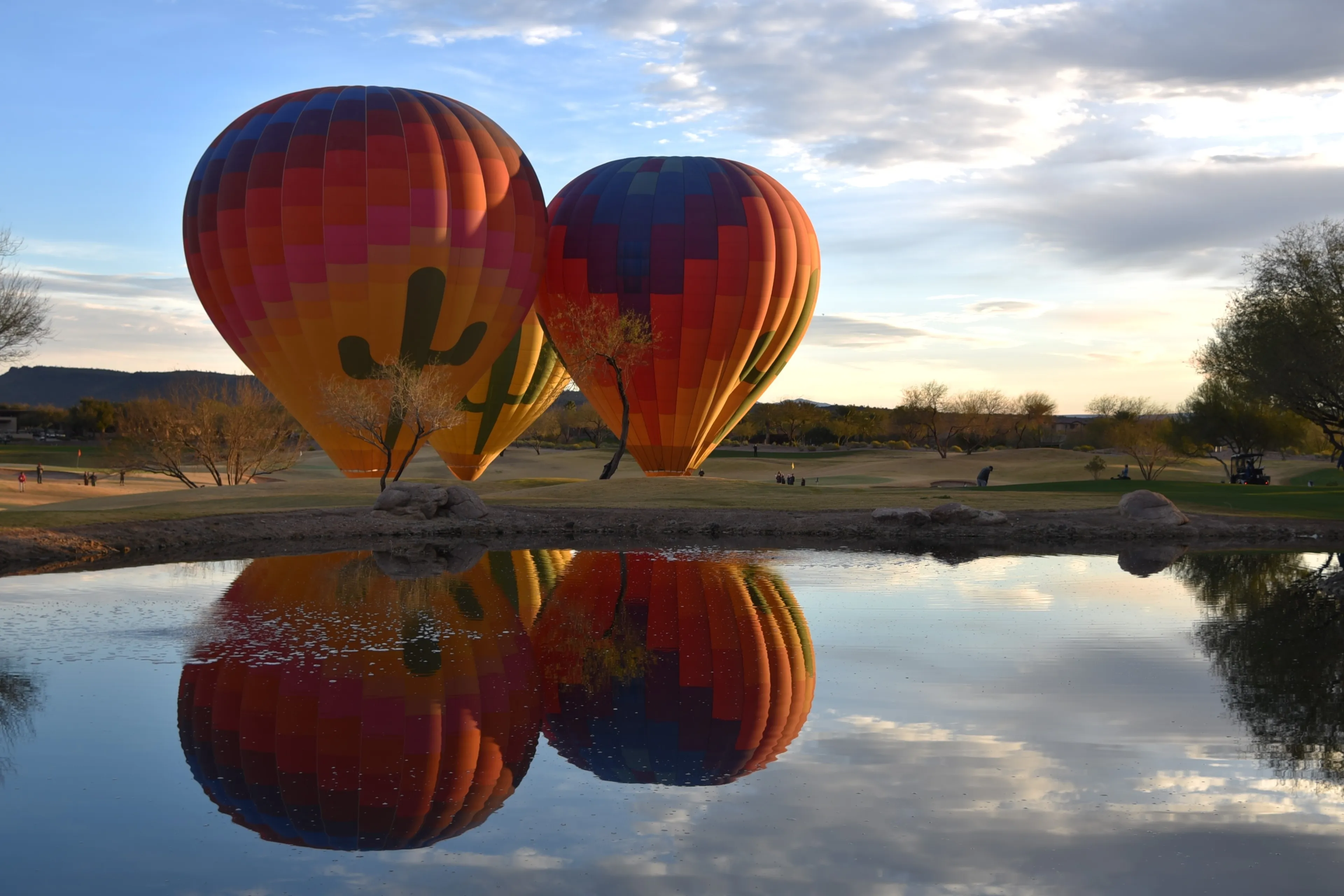 Peoria Arizona 3-6-2023 Hot air balloons being readied for flight with reflection in a lake
