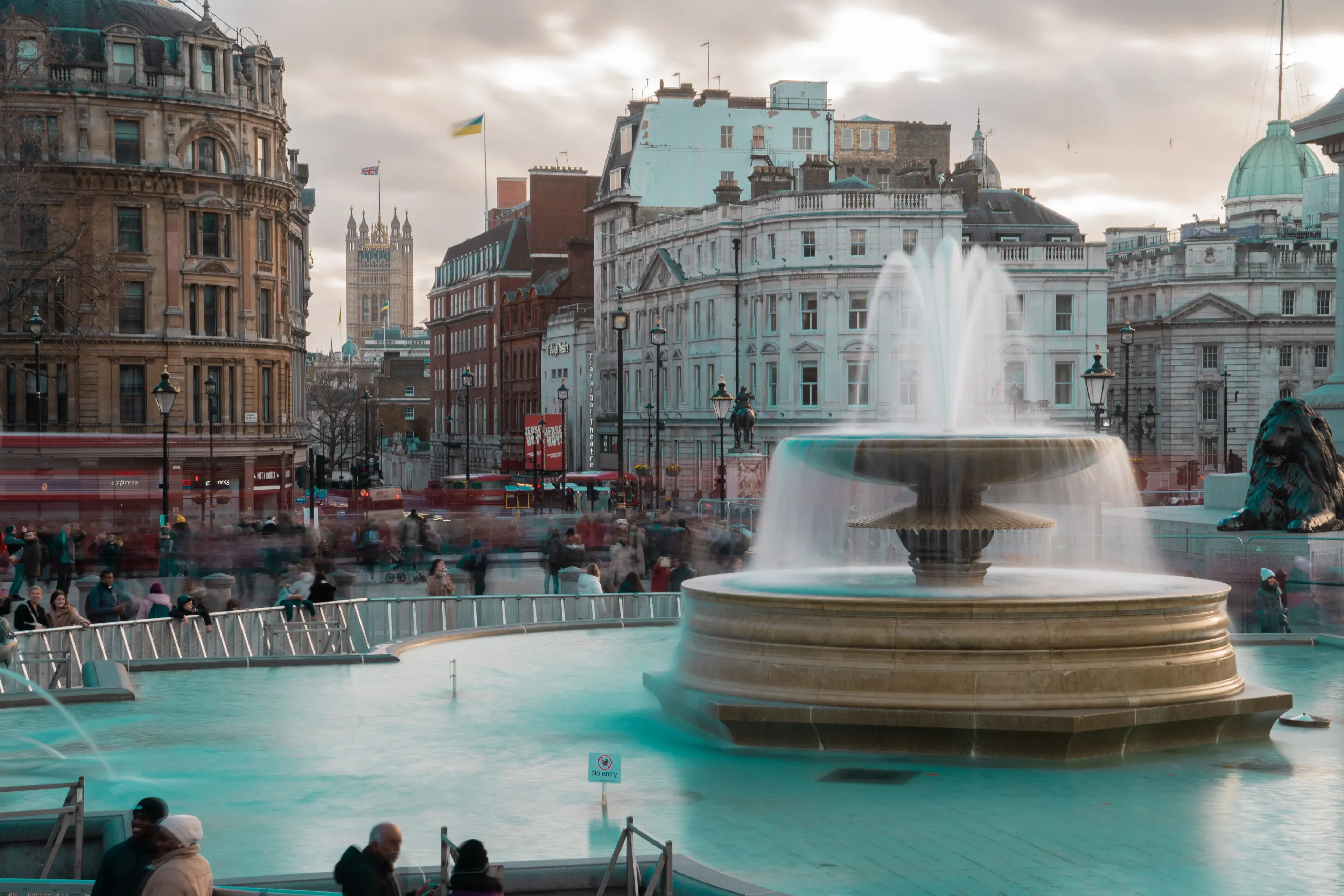 Long exposure photo of the iconic Trafalgar Square fountain with blurred crowd in London, England. Long exposure photo of the iconic Trafalgar Square fountain with blurred crowd in London, England.