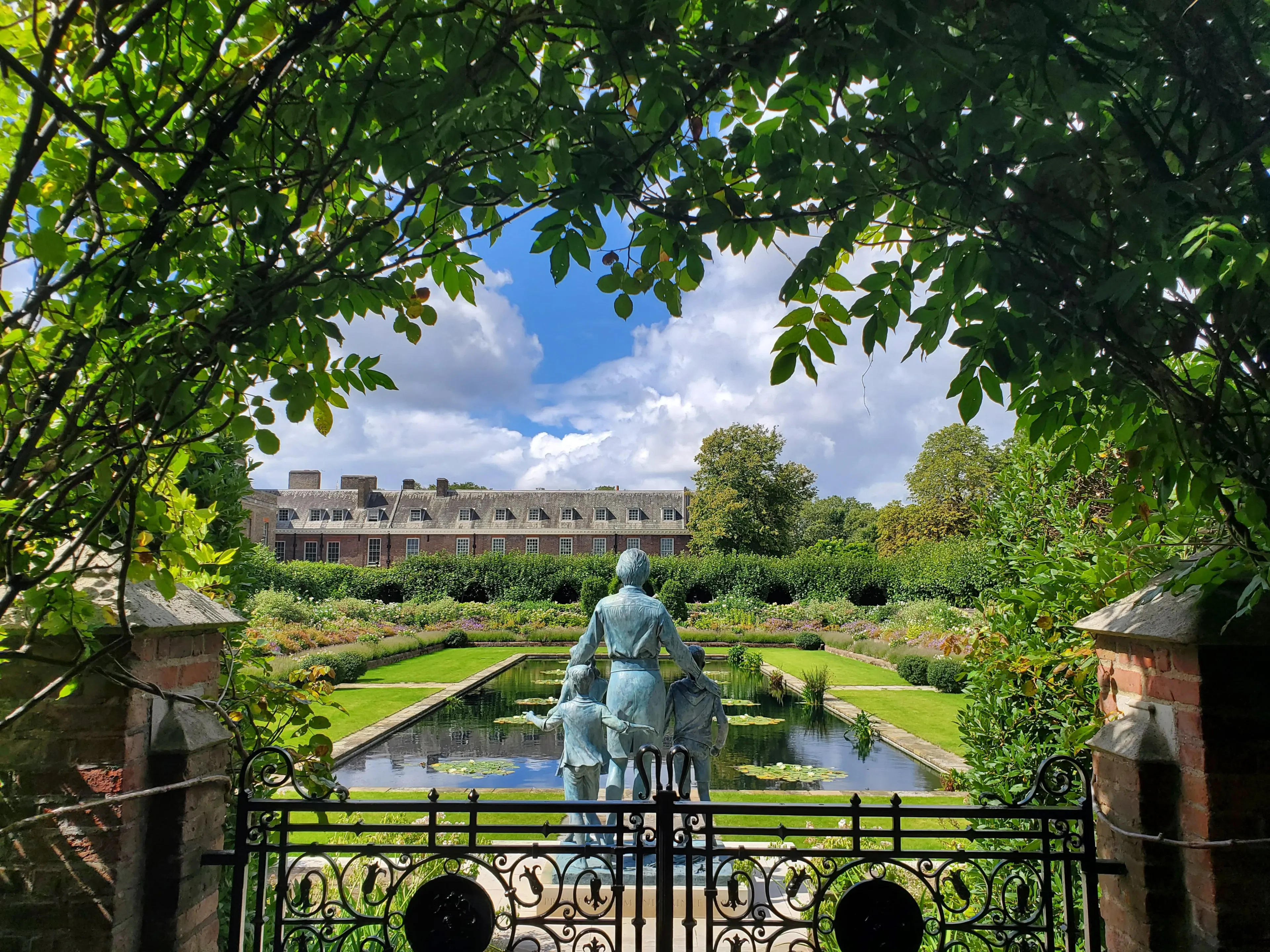 A peaceful view of the Sunken Garden with a sculpture at Kensington Palace in London
