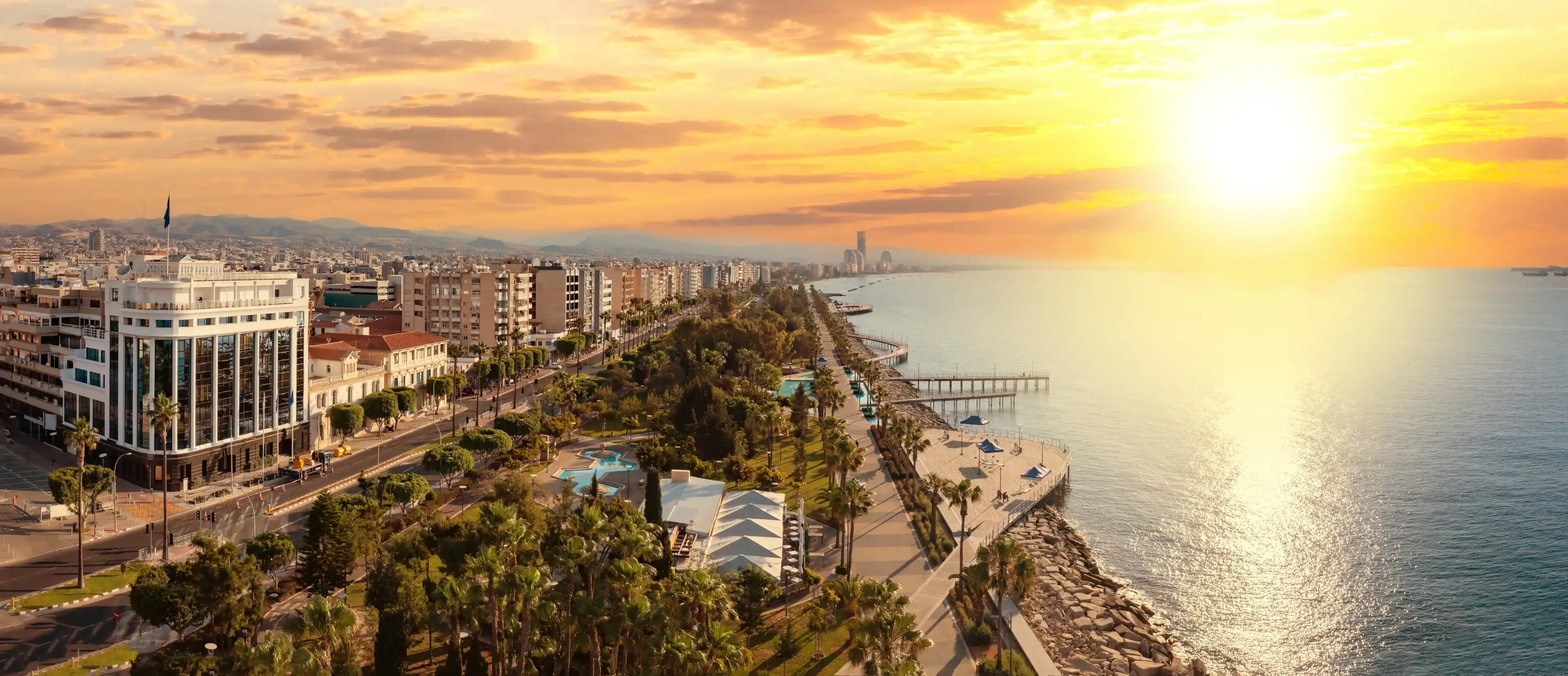 Sunset in Cyprus. Limassol beach. Embankment with piers. Cyprus on summer evening. Panorama Limassol resort. Urban landscape with hotels near sea. Cyprus tourism. Panorama Limassol view from drone