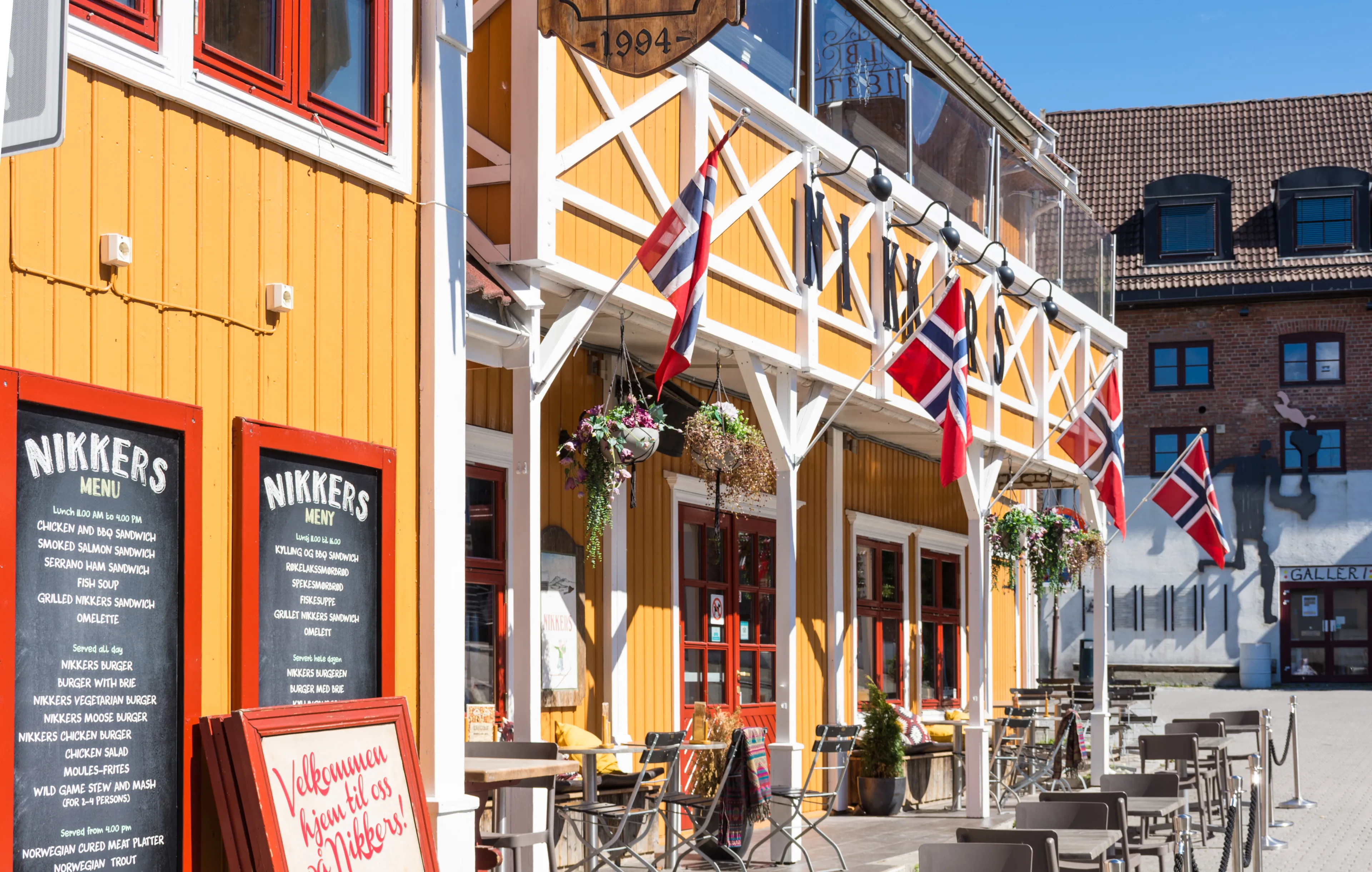 Lillehammer, Norway - August 5 2018: Colorful wooden building with Norwegian flags in Lillehammer