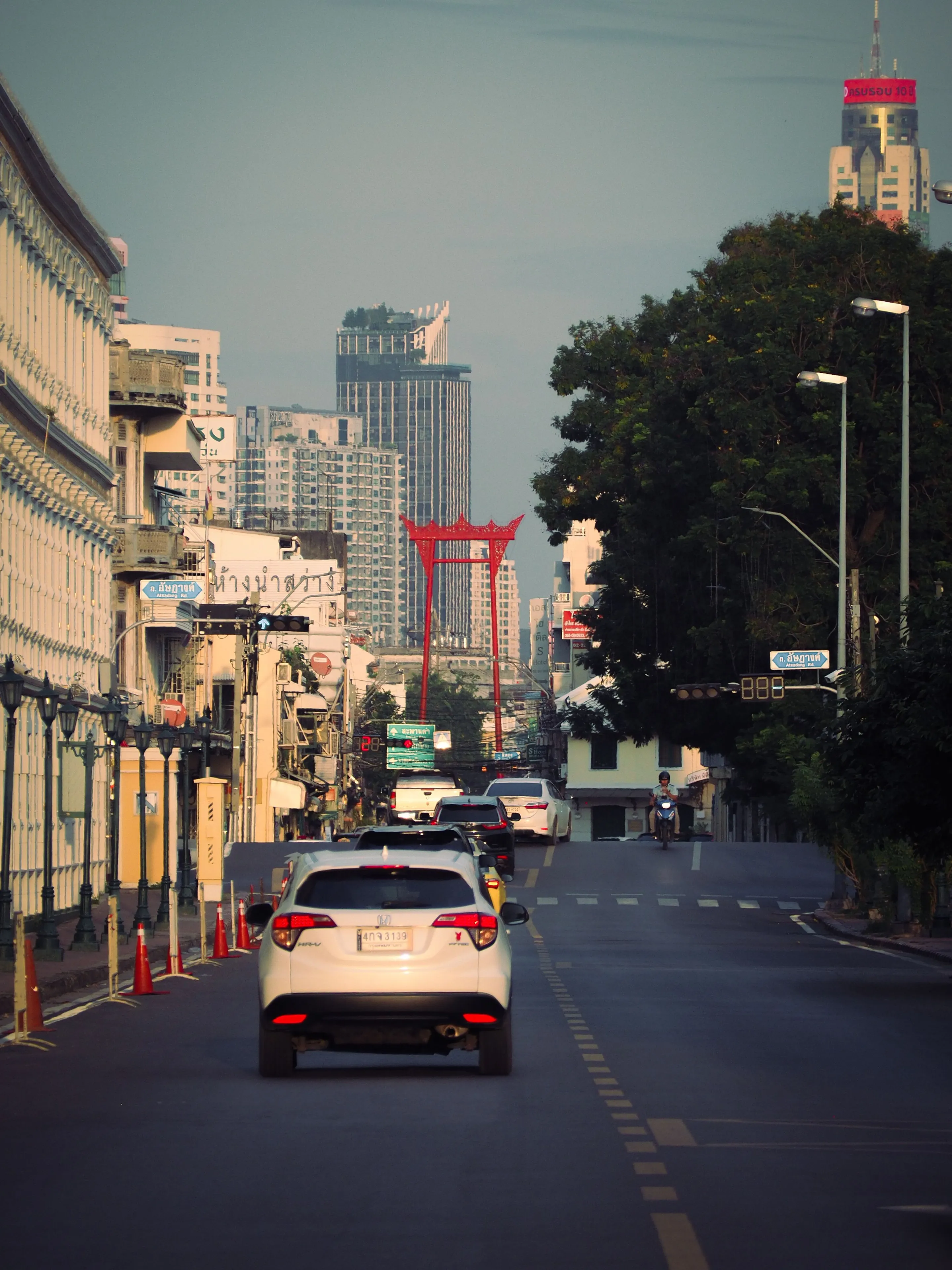 Street view in Bangkok featuring the iconic Giant Swing amidst urban traffic and city life