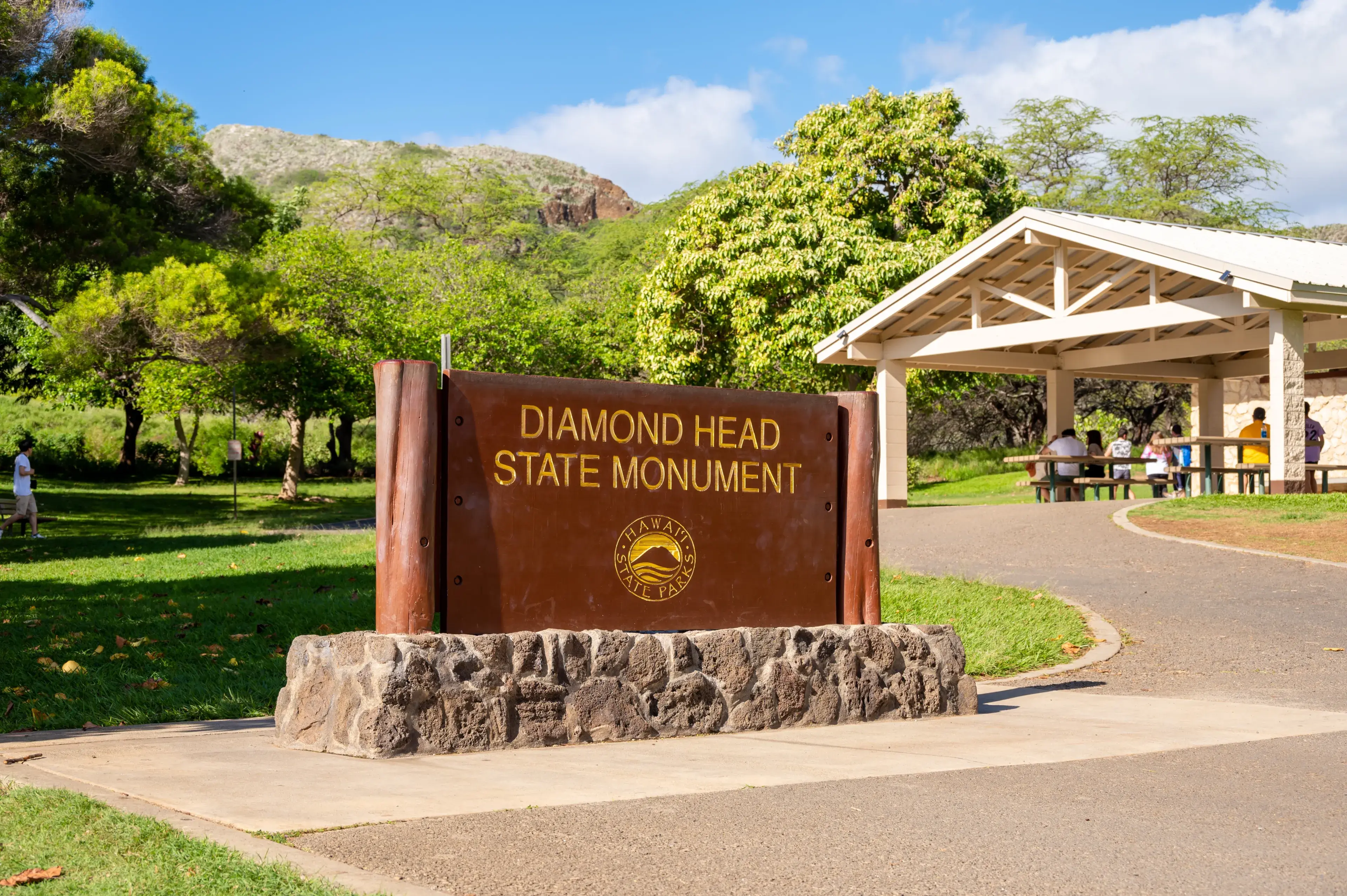 Honolulu, Hawaii - December 27, 2022: tourists at the Diamond Head entrance sign at the Diamond Head State Monument. Honolulu, Hawaii - December 27, 2022: tourists at the Diamond Head entrance sign at the Diamond Head State Monument.