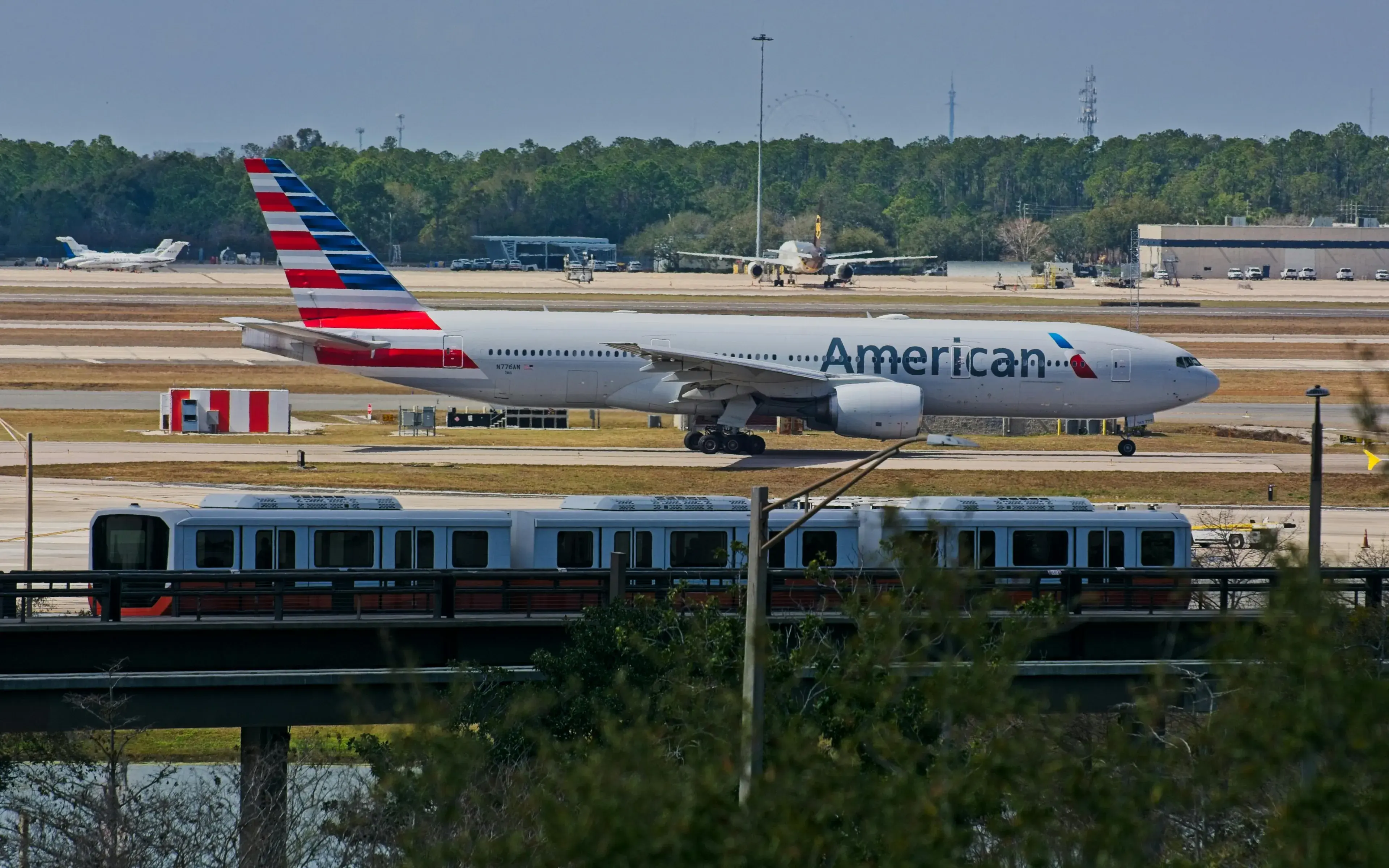 American Airlines Boeing 777 taxiing at Orlando International Airport with city rail in foreground American Airlines Boeing 777 taxiing at Orlando International Airport with city rail in foreground