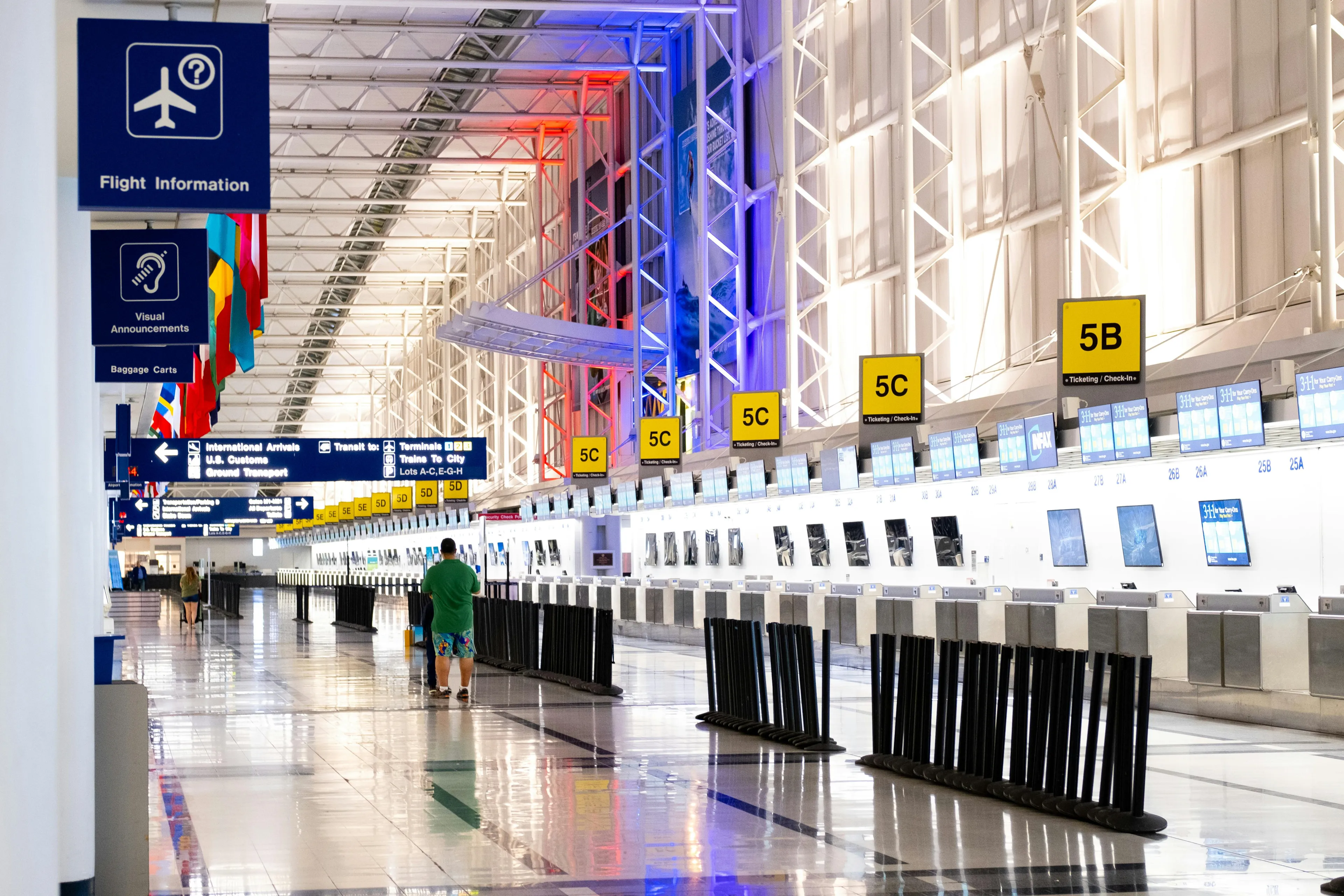 Wide view of Chicago airport terminal showcasing architecture and check-in counters. Flags and signages add vibrant detail.  More info  Share