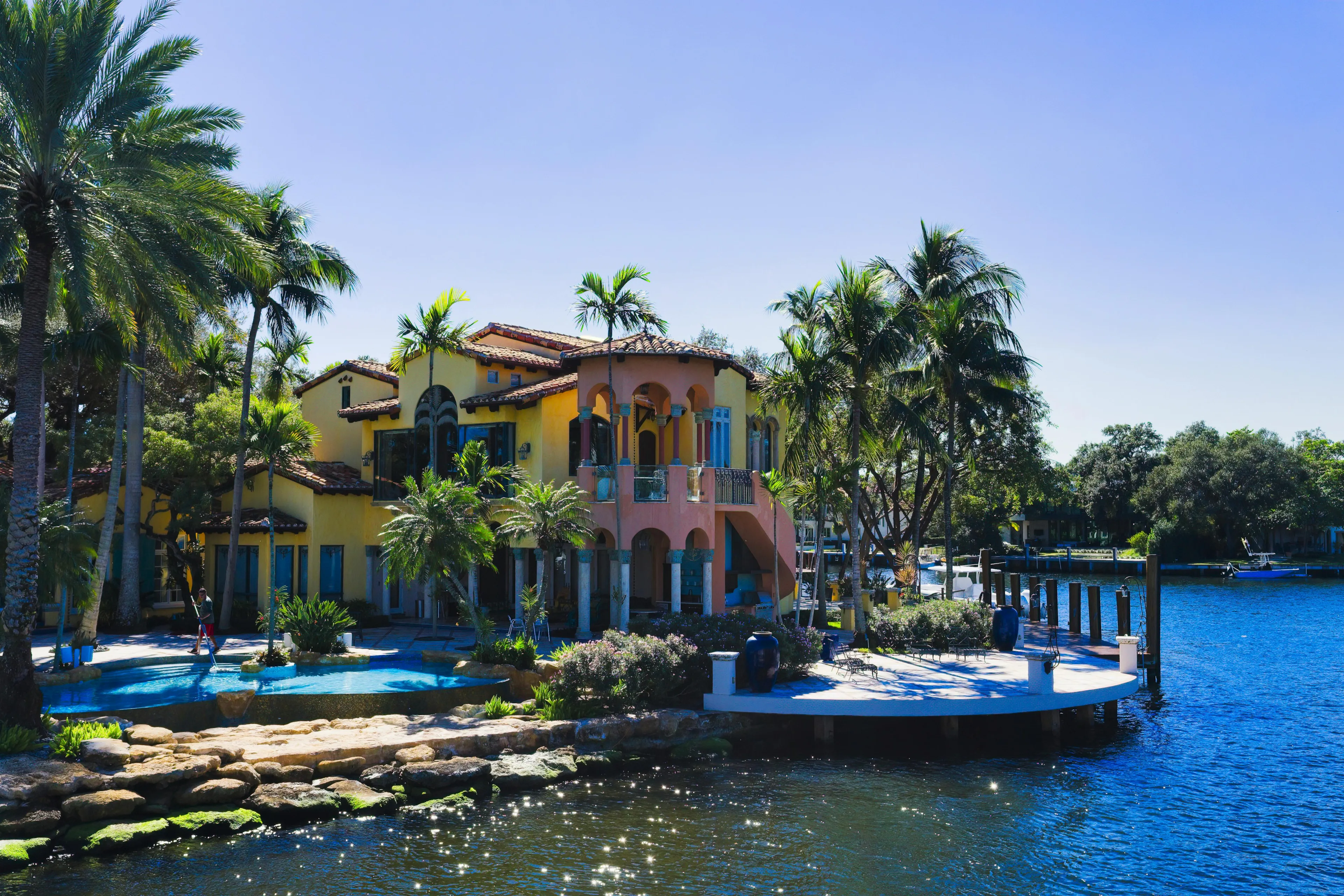 Stunning view of a colorful mansion with palm trees by the water in Fort Lauderdale, Florida.  More info  Share