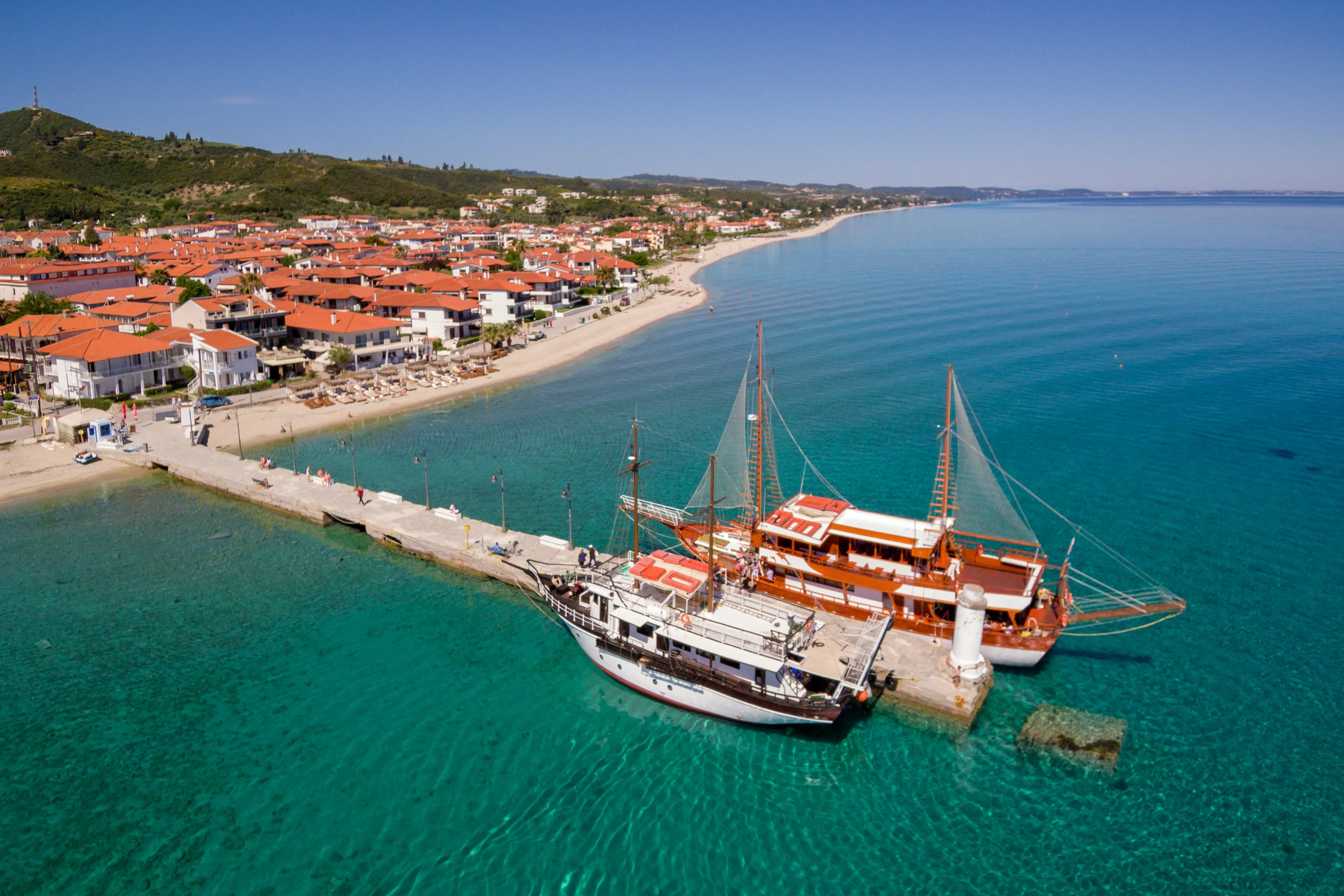 Aerial view of Pefkochori village port with two ships offering daily cruises