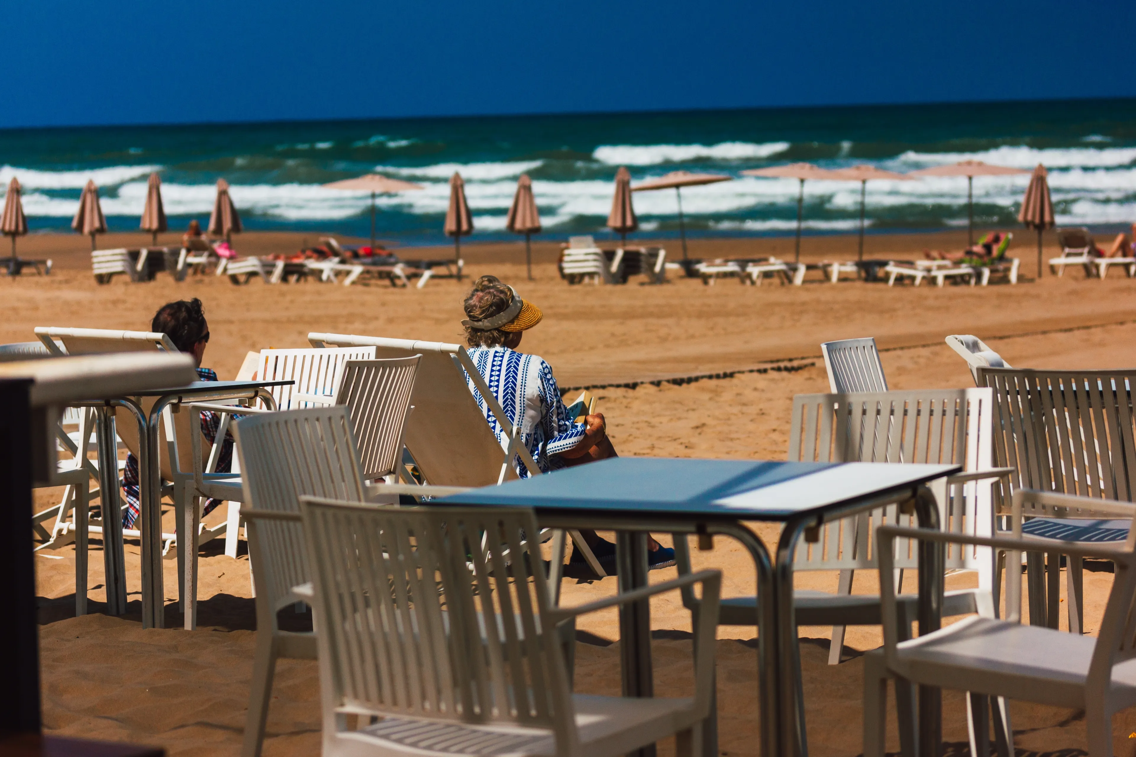Gandia, Spain. June 1, 2024 Scene of city beach with people relaxing on the beach, ocean in summer. Vacation on the coast of the resort. Cafe terrace.
