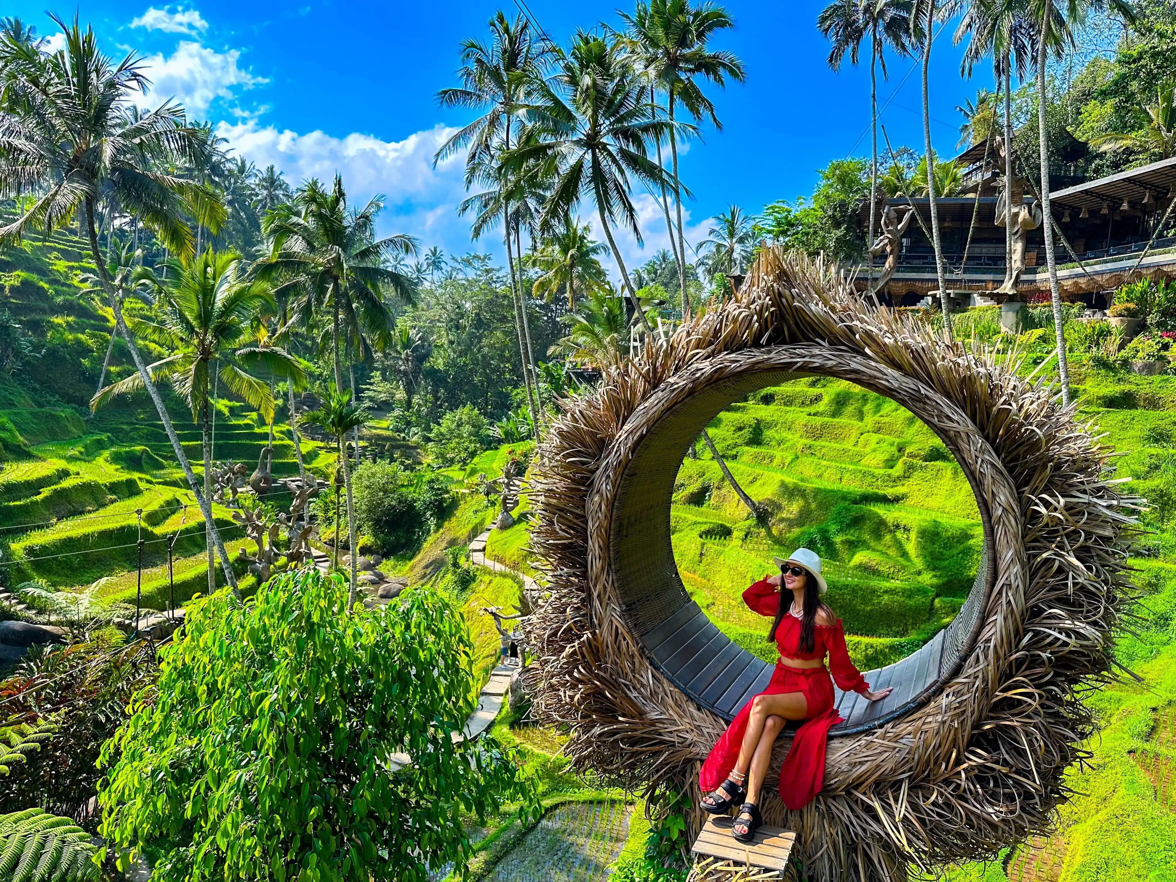 Ceking Rice Terrace (Tegalalang Rice Terrace), Ubud, Bali, Indonesia, October 2023. A stylish girl in a red dress, and a straw hat sitting on the spot view overlooking the tropical paradise Ceking Rice Terrace (Tegalalang Rice Terrace), Ubud, Bali, Indonesia, October 2023. A stylish girl in a red dress, and a straw hat sitting on the spot view overlooking the tropical paradise