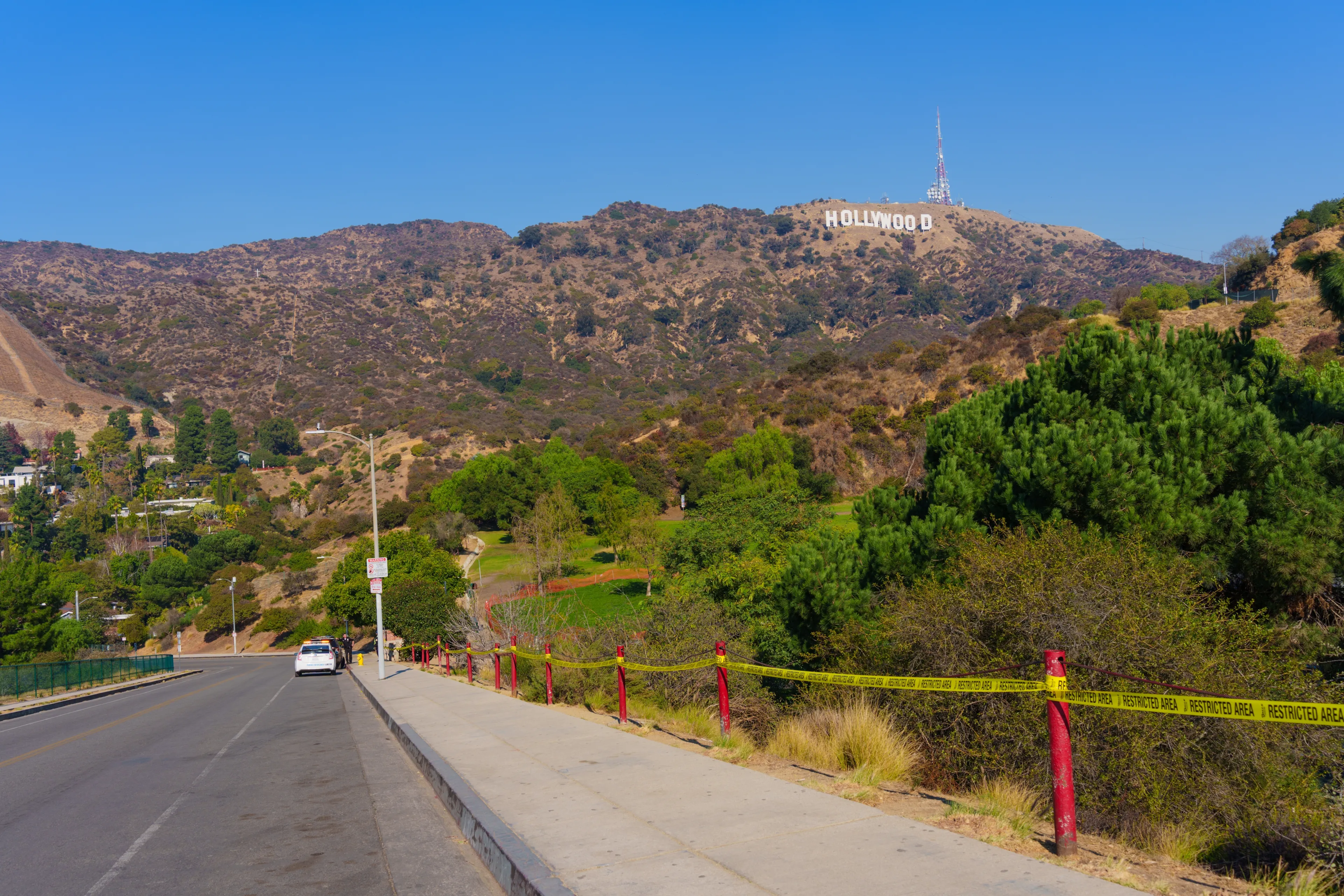 Los Angeles, California - January 9, 2025: The Hollywood Sign looms in the background, framed by emergency barriers and dry brush, illustrating the challenges of wildfires in Los Angeles.