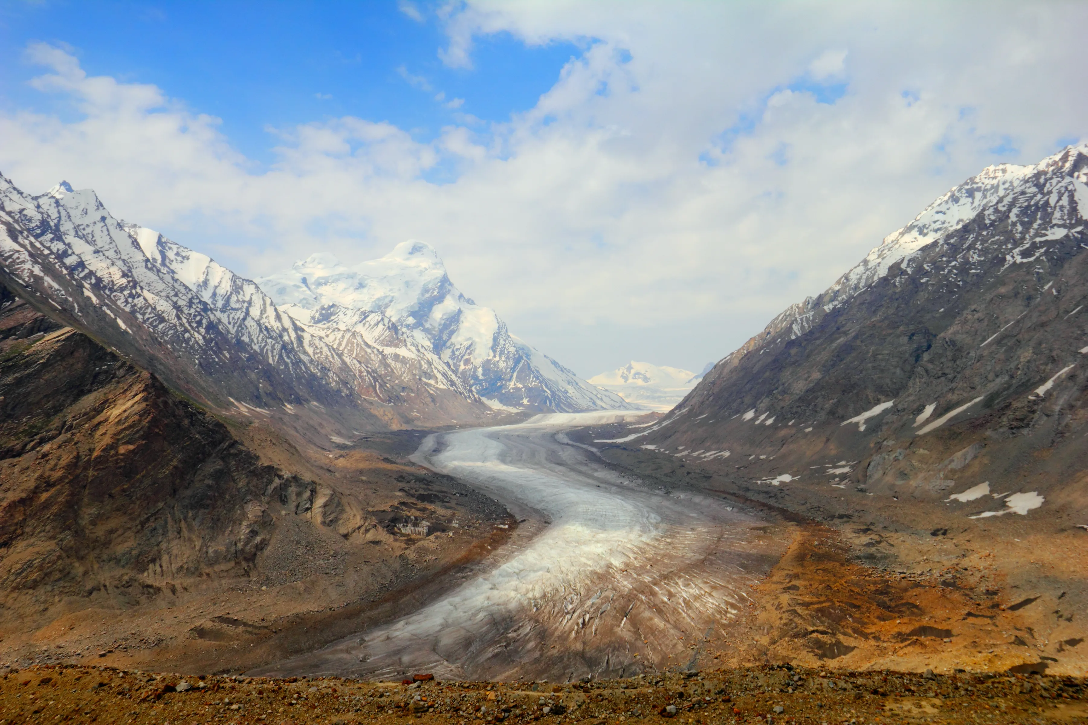 Beautiful nature scenery with melting glacier between two mountain range covered with snow against the background of cloudy sky in Zanskar valley, Ladakh, Jammu & Kashmir, Northern India, Central Asia