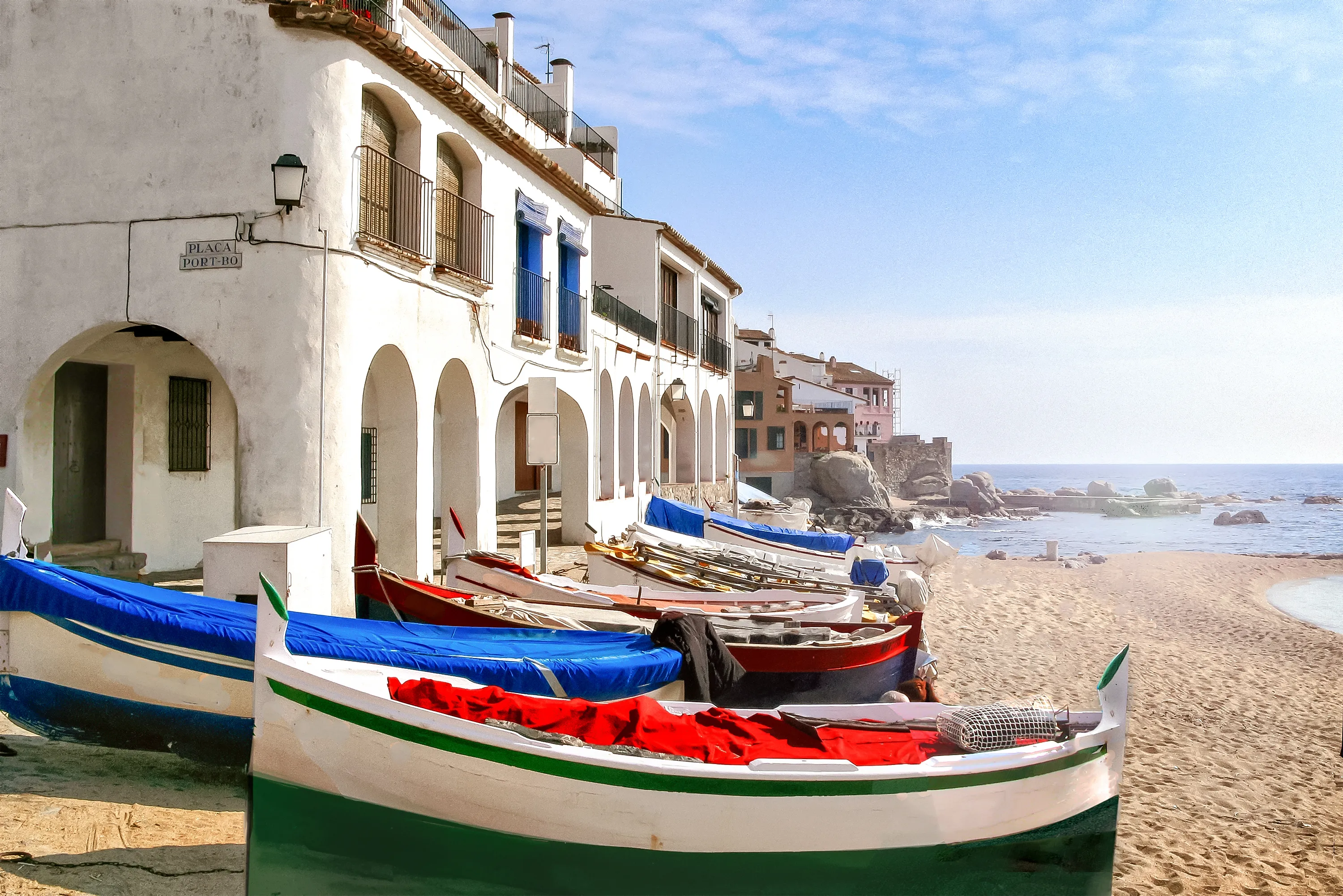 Calella de Palafrugell, Spain, Mediterranean coast fishing village - Traditional building with arches and fishing boats on the beach.