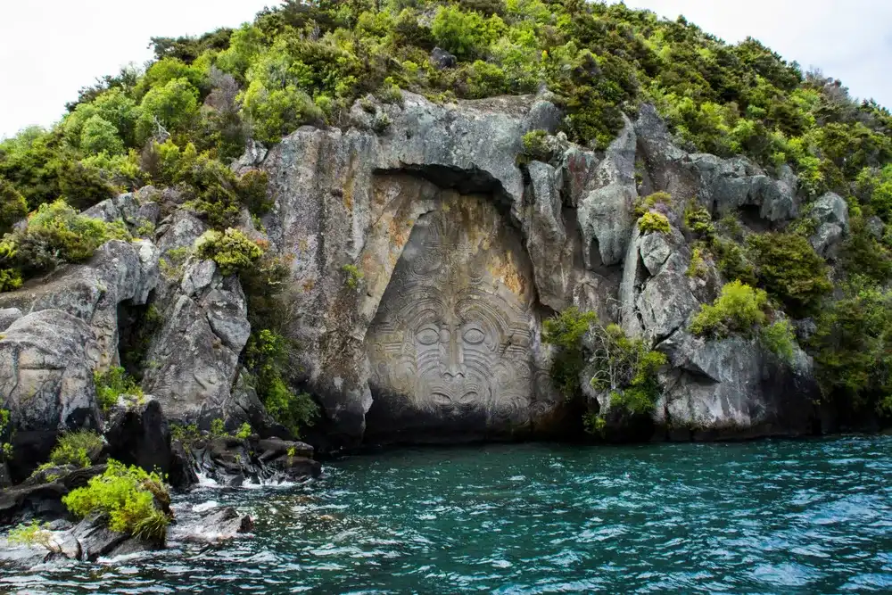 Travel New Zealand, North Island, Taupo. Cruise view of Iconic Maori rock carving in the rock on Great Lake Taupo. Popular tourist attraction/activity.