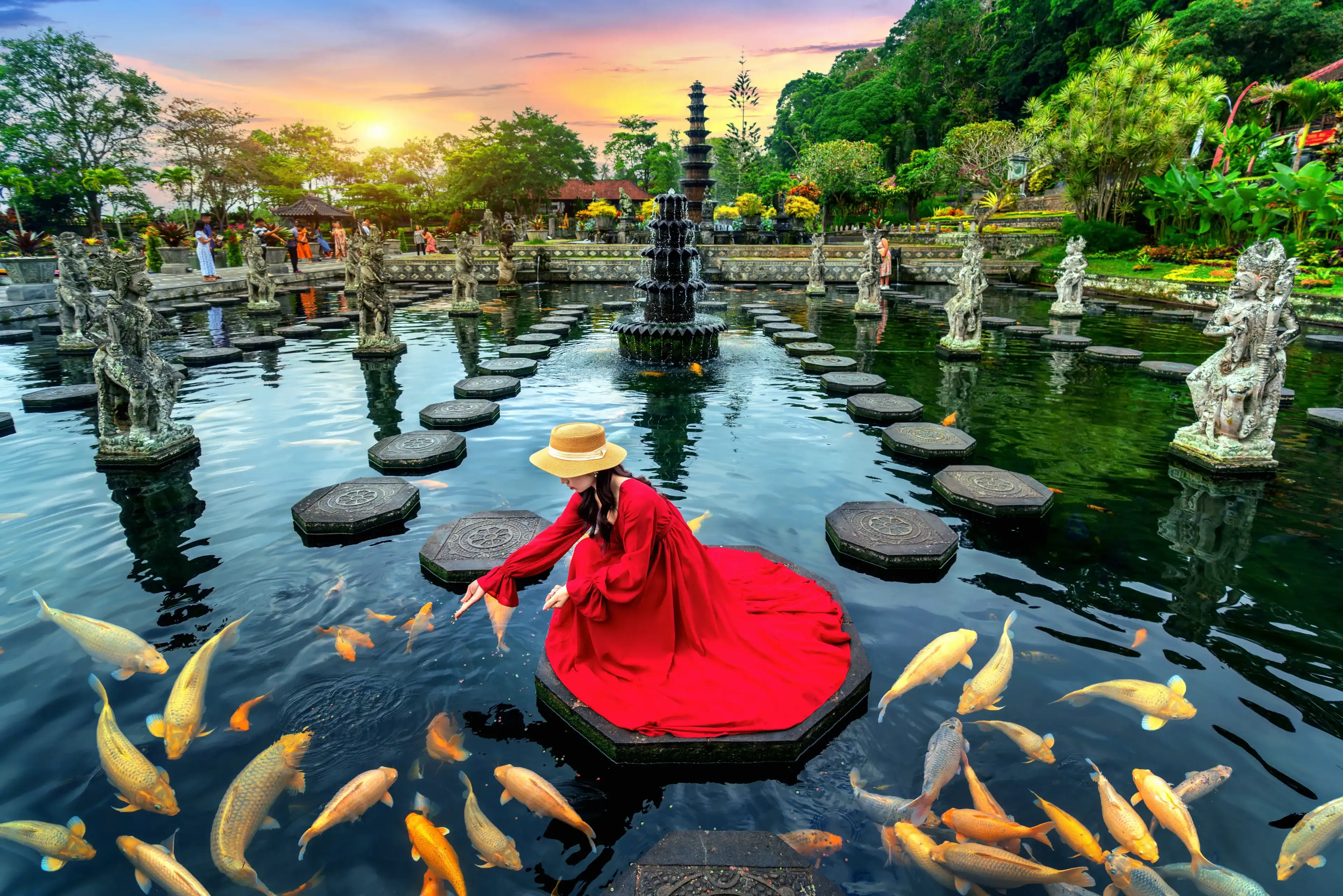 Woman feeding colorful fish in pond at Tirta Gangga Water Palace in Bali, Indonesia. Woman feeding colorful fish in pond at Tirta Gangga Water Palace in Bali, Indonesia.