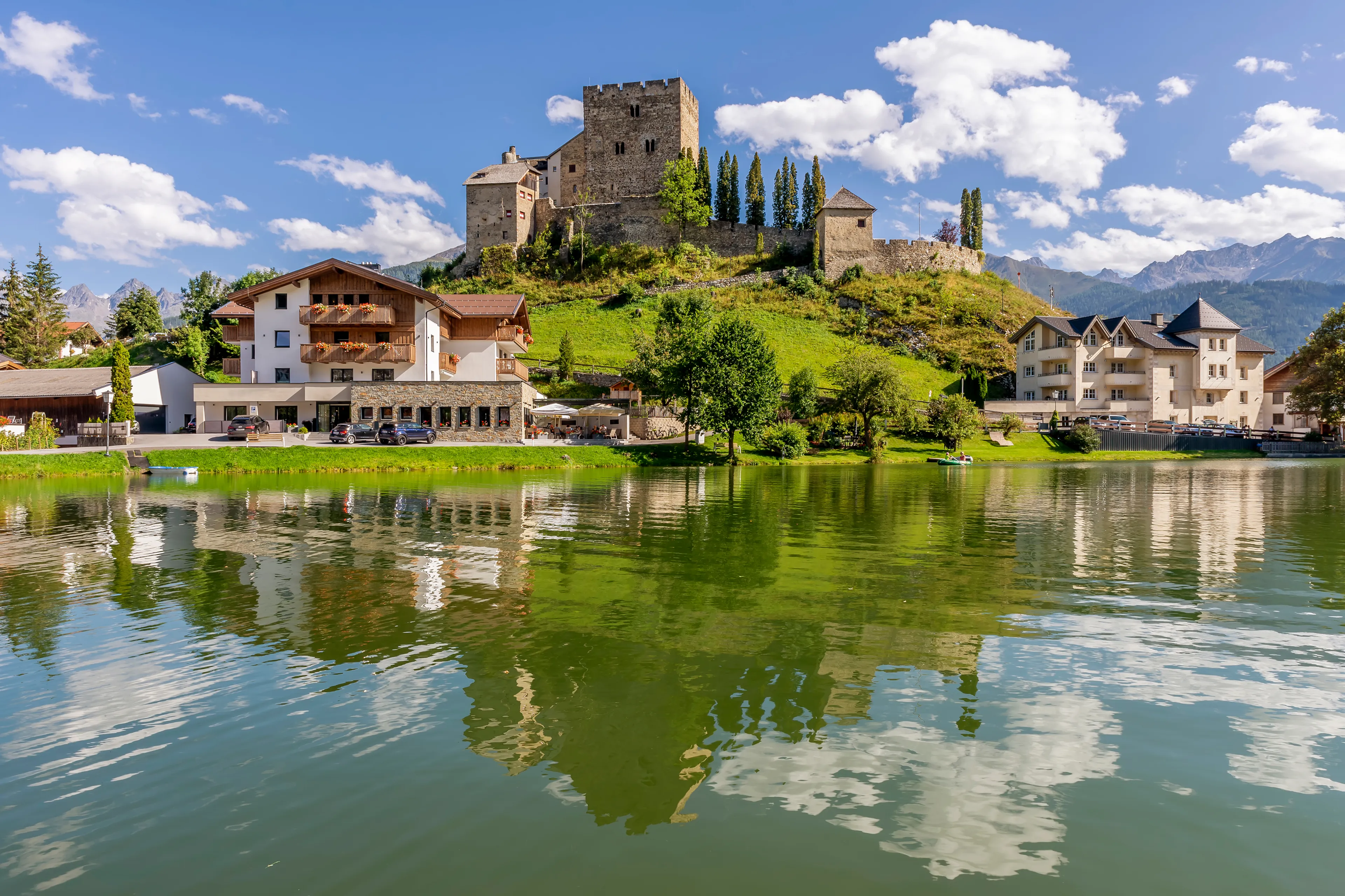 Laudegg Castle is reflected in the lake below on a beautiful sunny day, Ladis, Serfaus, Tyrol, Austria
