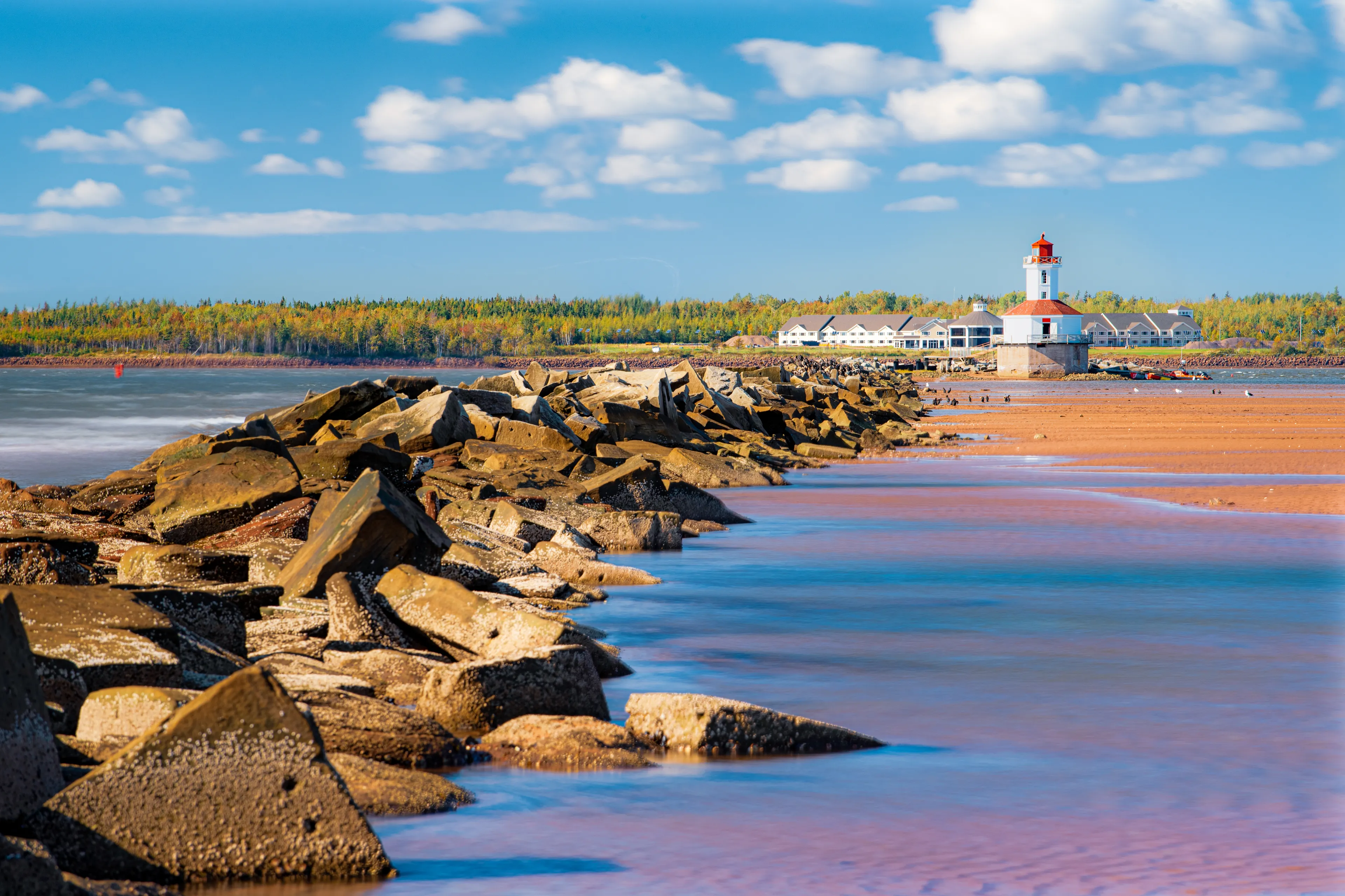 Summerside, Prince Edward Island / Canada - September 27, 2019: A lighthouse stands at the end of a rocky breakwater at the entrance to Summerside Harbour and the Bradshaw River in western PEI
