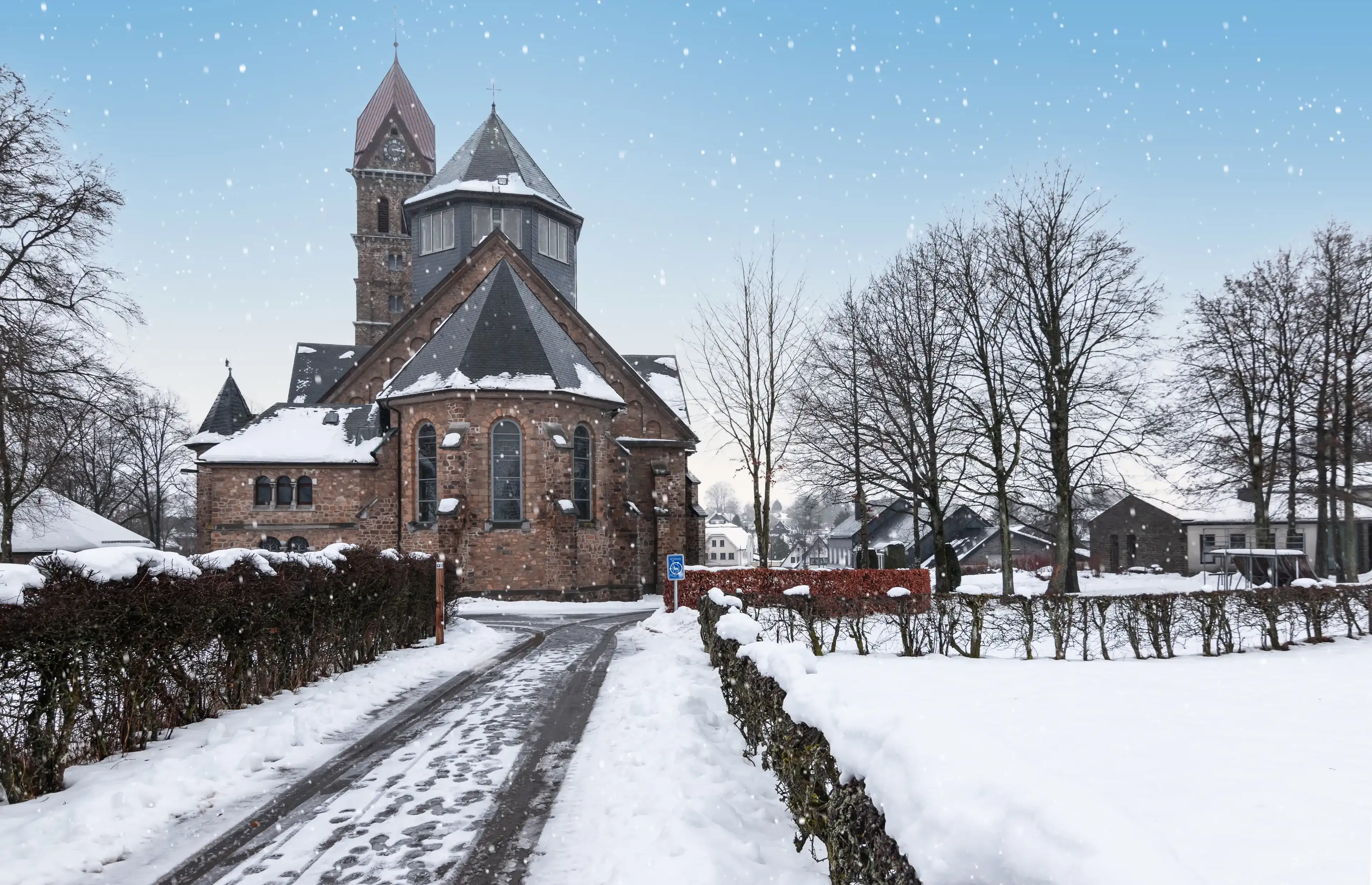 Catholic parish church and snowy street in Butgenbach, Ardennes, Belgium.