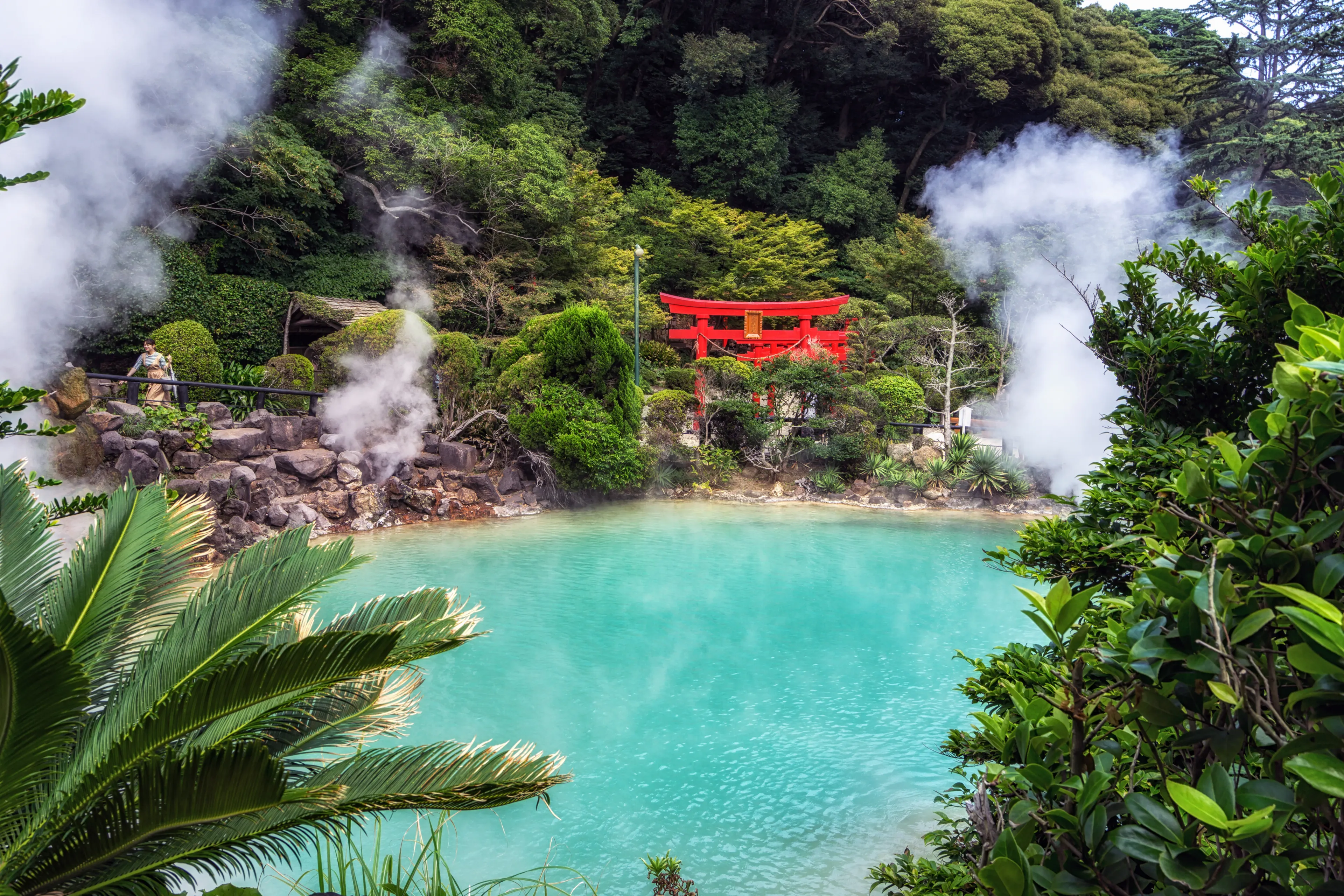 umi jigoku or sea hell taken in beppu with steamy hot springs geyser steaming off the cobalt water. Red torii gates nearby the geyser. Taken in Beppu, Japan