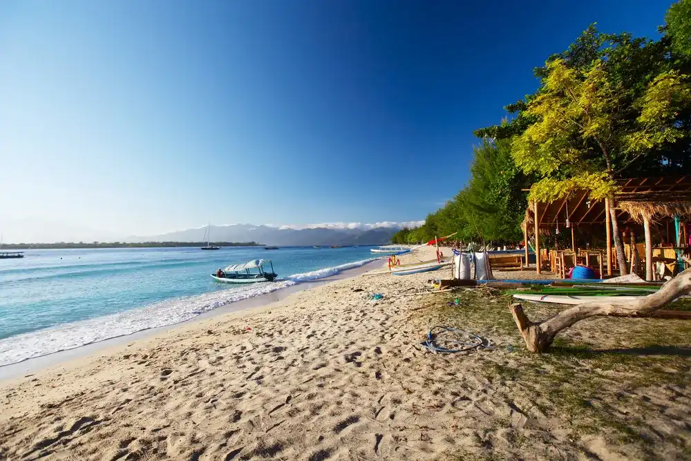 Tropical sandy beach with buildings and boats in a sea. Gili Trawangan, Indonesia