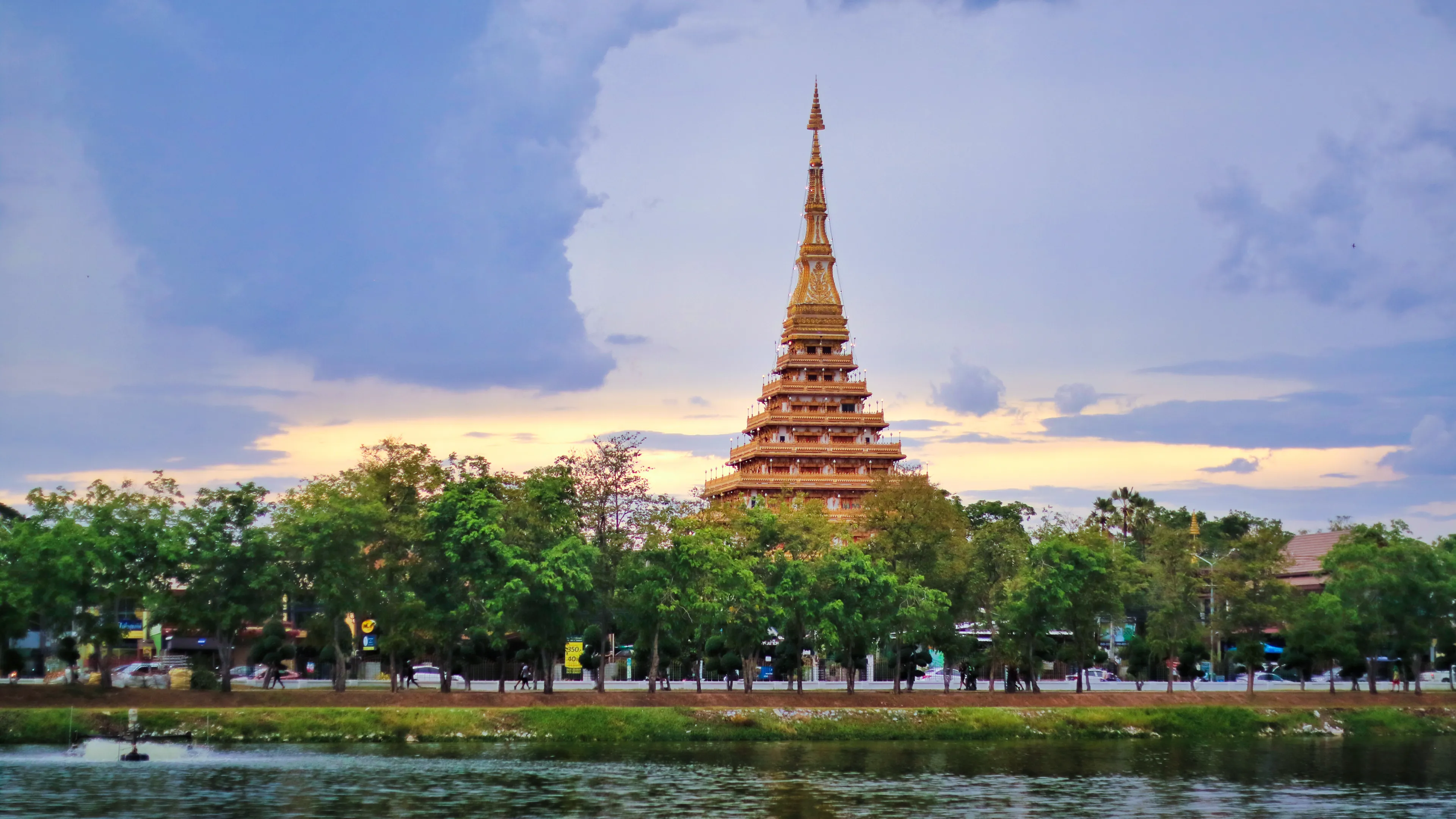 Beautiful sunset view of golden nine storey Called "Phra Mahathat Kaen Nakhon" or "Wat Nong Wang" surrounded with lake at Khon Kaen town.