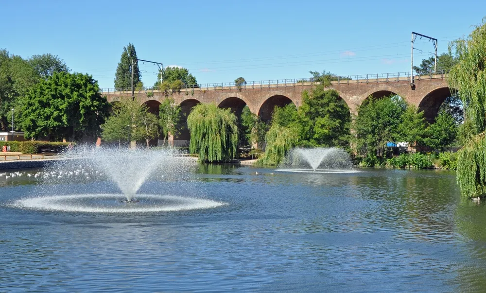 Chelmsford, Essex, United Kingdom, August 5, 2022, Central Park public open space in centre of city with lake and water fountains and railway viaduct. 