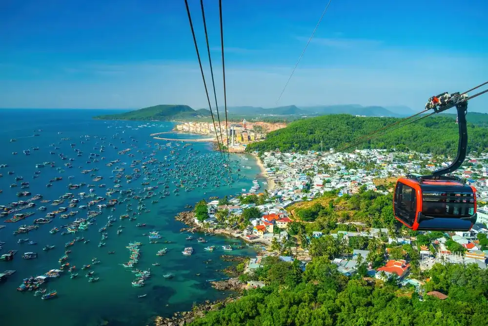 The longest cable car situated on the Phu Quoc Island in South Vietnam and below is traditional fishermen boats lined in the harbor of Duong Dong town in the popular Hon Thom island. Travel concept.