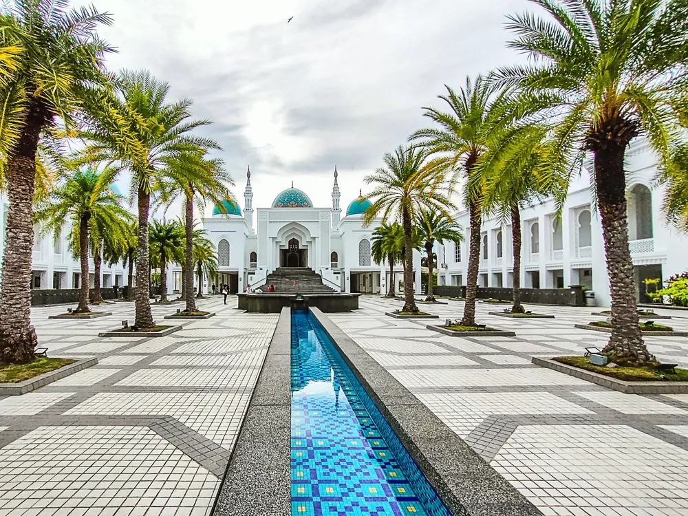Al-Bukhary public mosque in Alor Setar a modern architecture and unique manmade building during during sunset with view of blue pond in front. (noise visible blurry soft focus) Nature composition