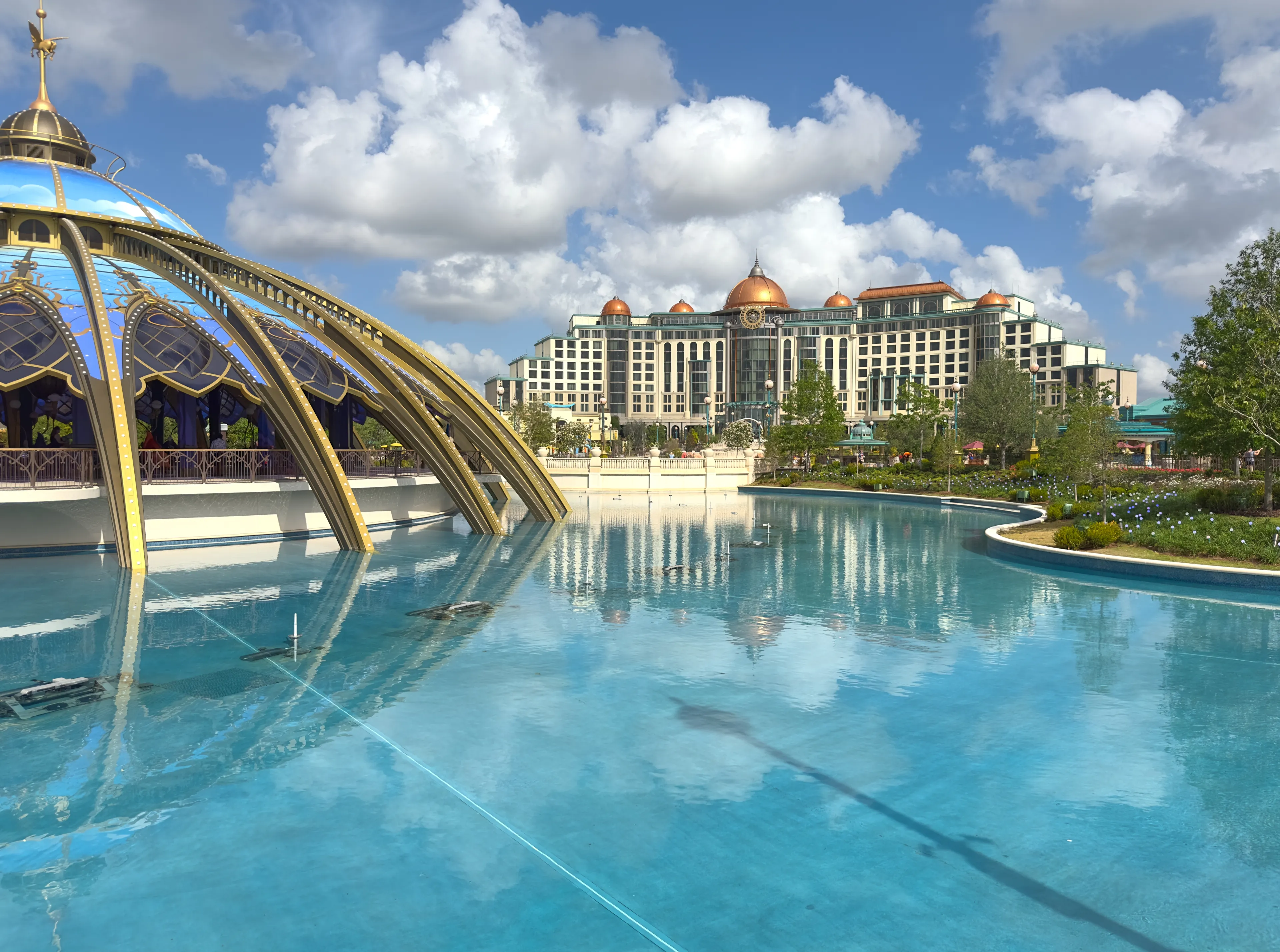 Orlando, Florida - May 2, 2025: View of the Grand Helios Hotel at Universal’s Epic Universe theme park, reflected in the lagoon under a bright blue sky.
