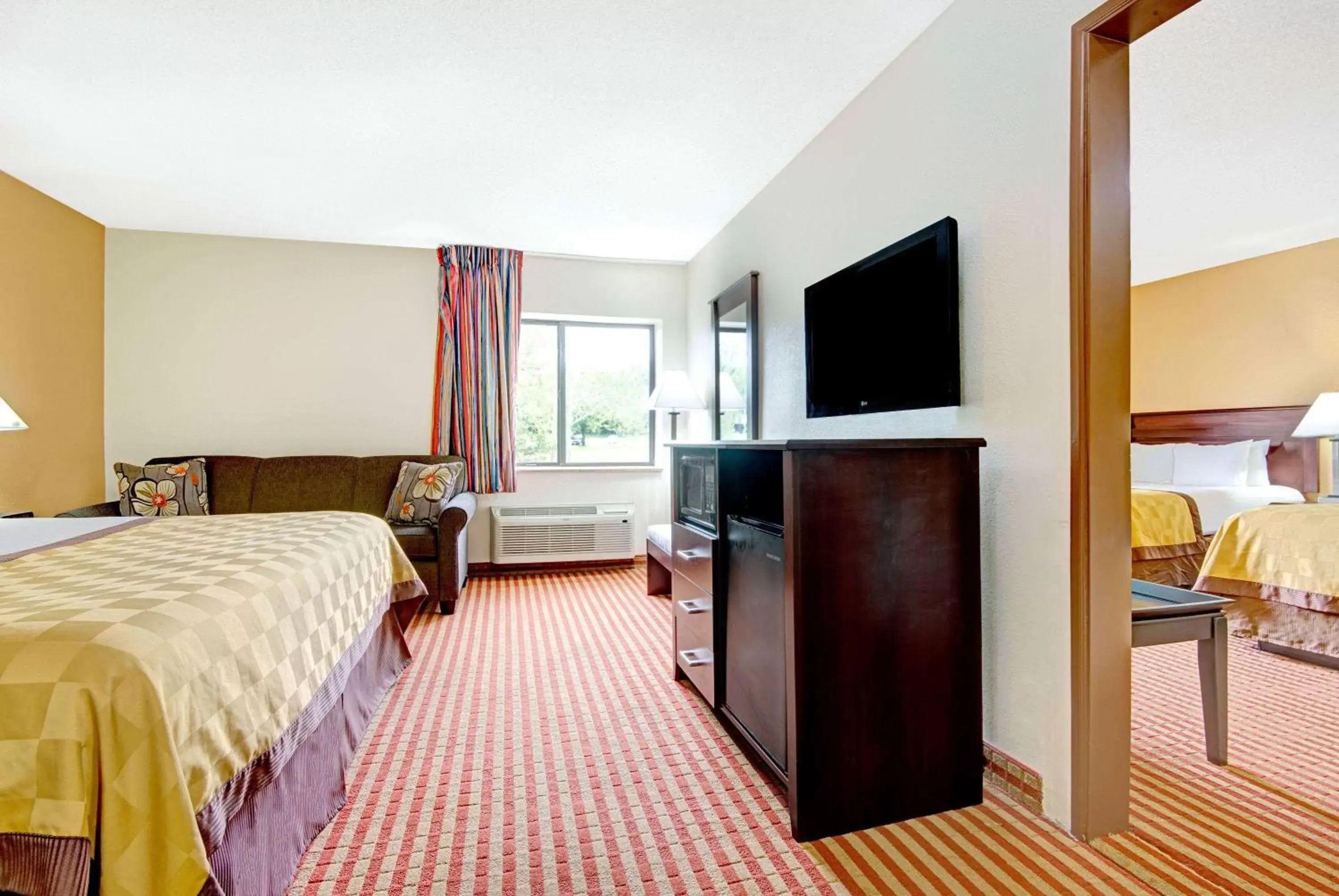 Bed, TV/Entertainment Center in Days Inn & Suites by Wyndham Kansas City - Royals Stadium