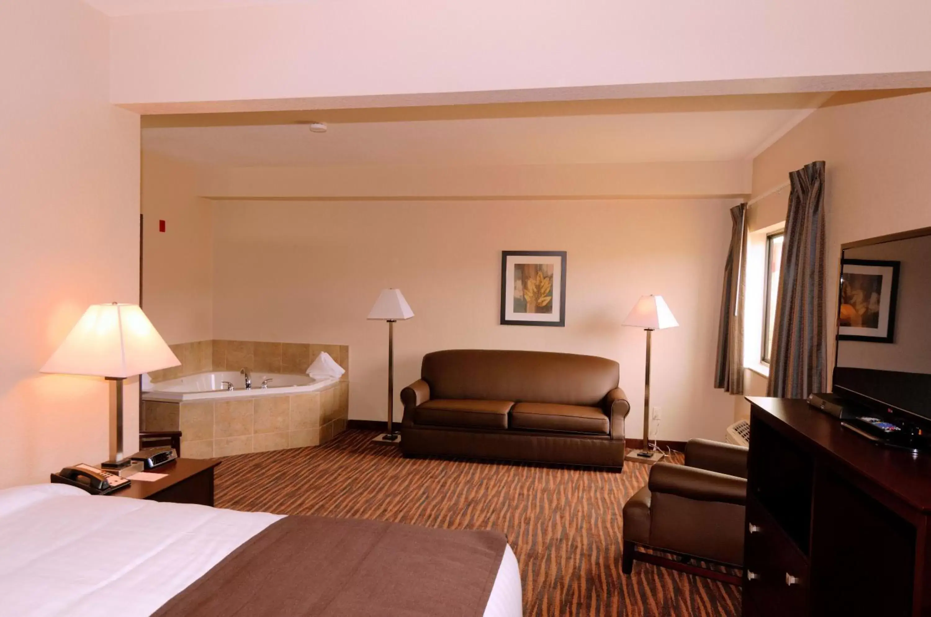 Bed, Seating Area in Cobblestone Inn & Suites - Denison | Oak Ridge