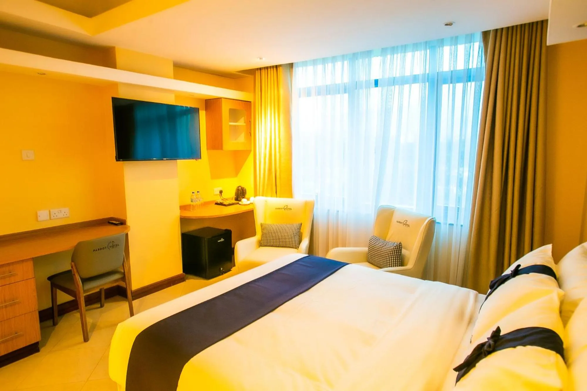 Communal lounge/ TV room, Bed in Parrot Hotel Arusha