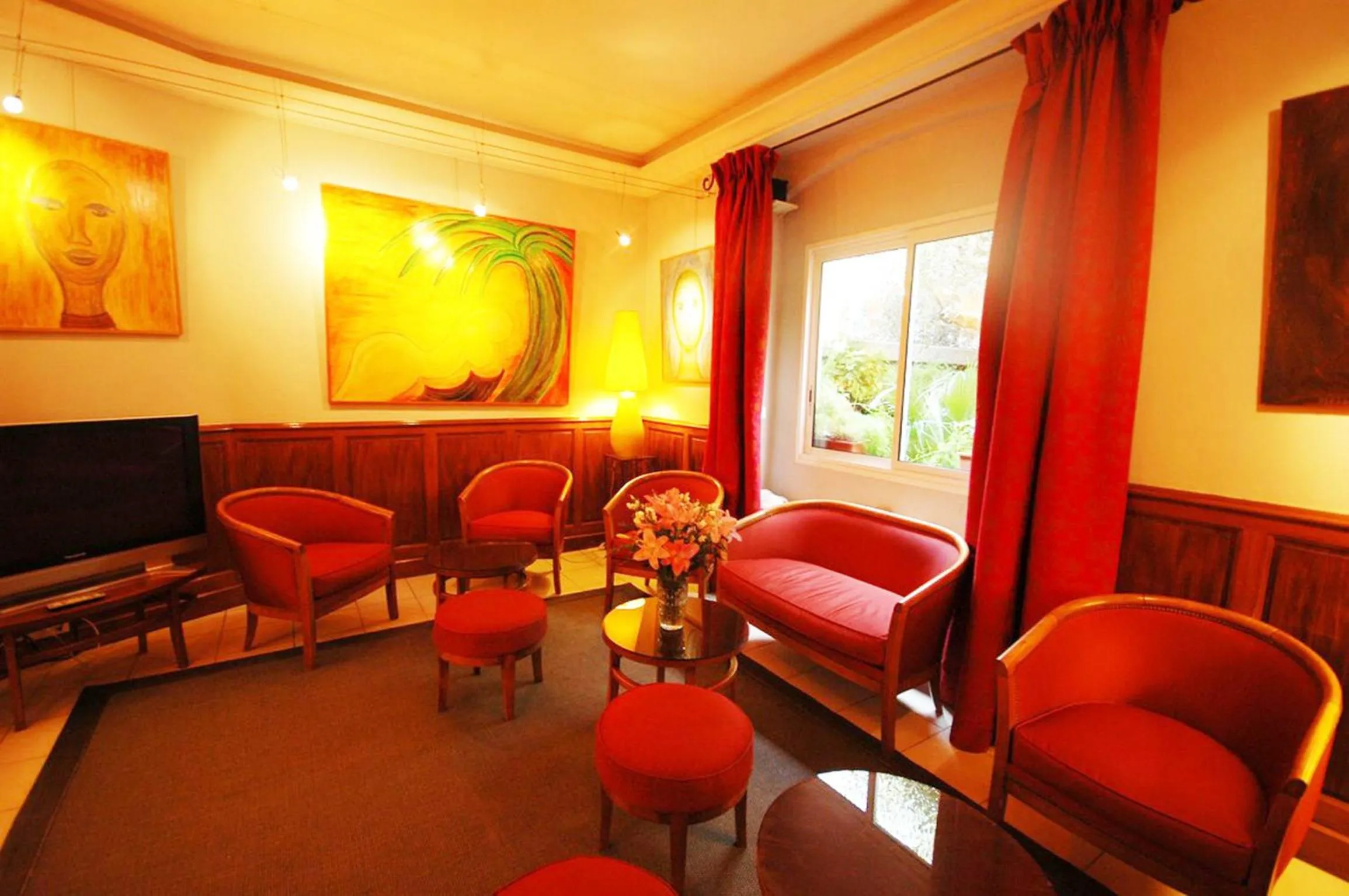Communal lounge/ TV room in Hôtel Les Palmiers