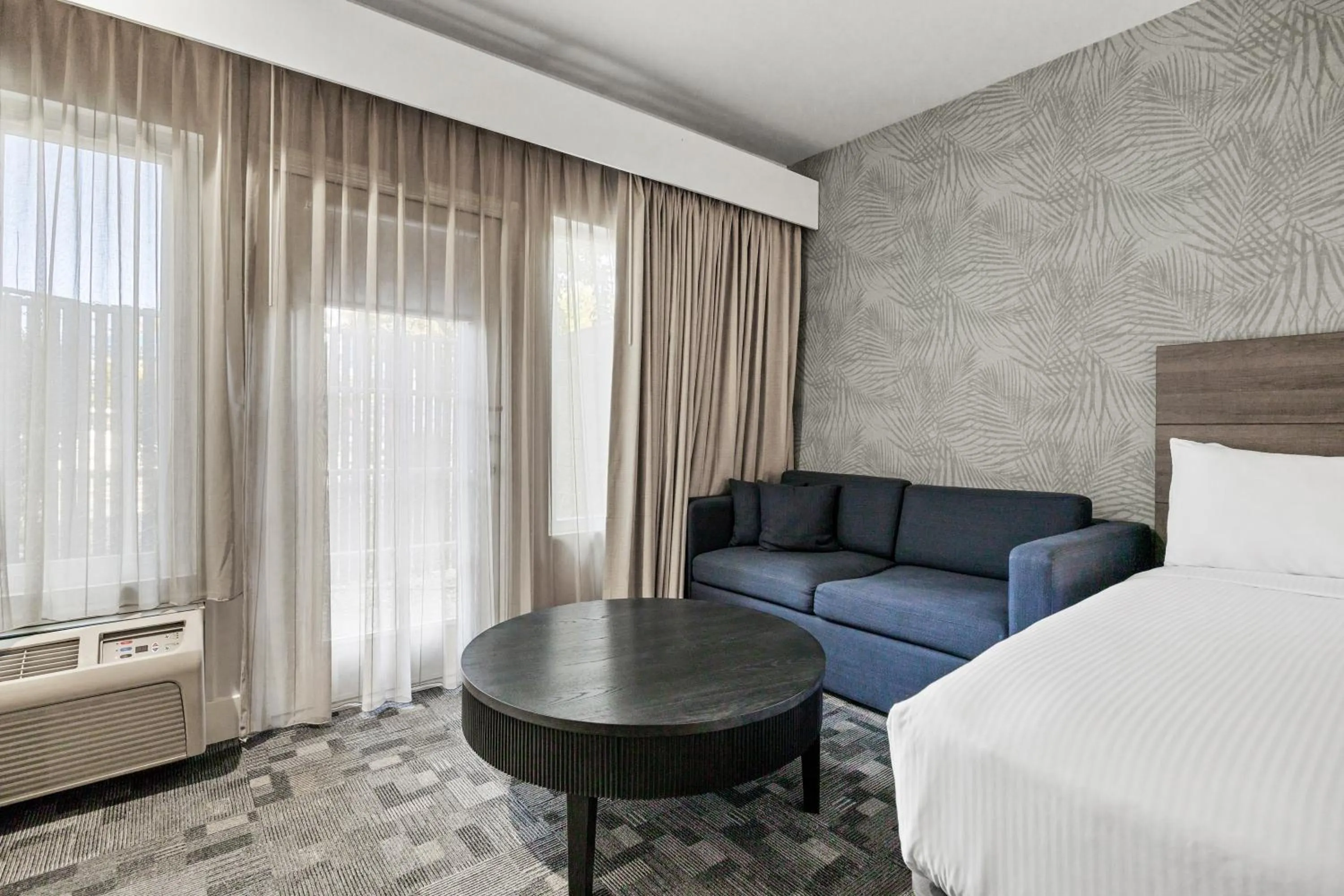 Seating area, Bed in University Park Inn & Suites, an Ascend Collection Hotel