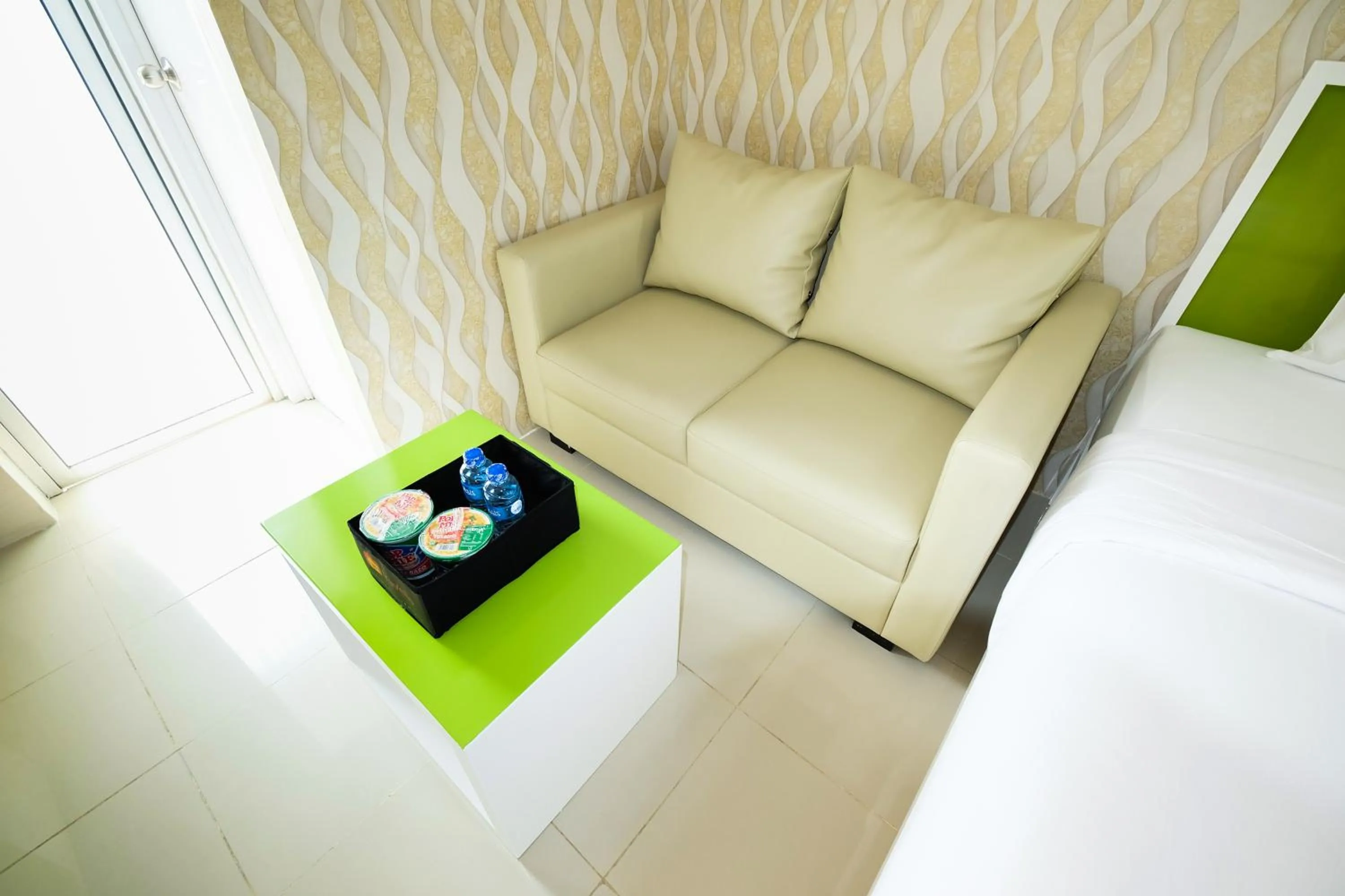 Seating area, Bed in Modern Studio Bassura City Apartment By Travelio