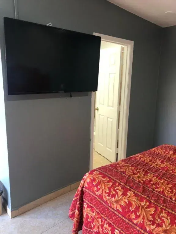 Bed, TV/Entertainment Center in The Fly Inn Motel